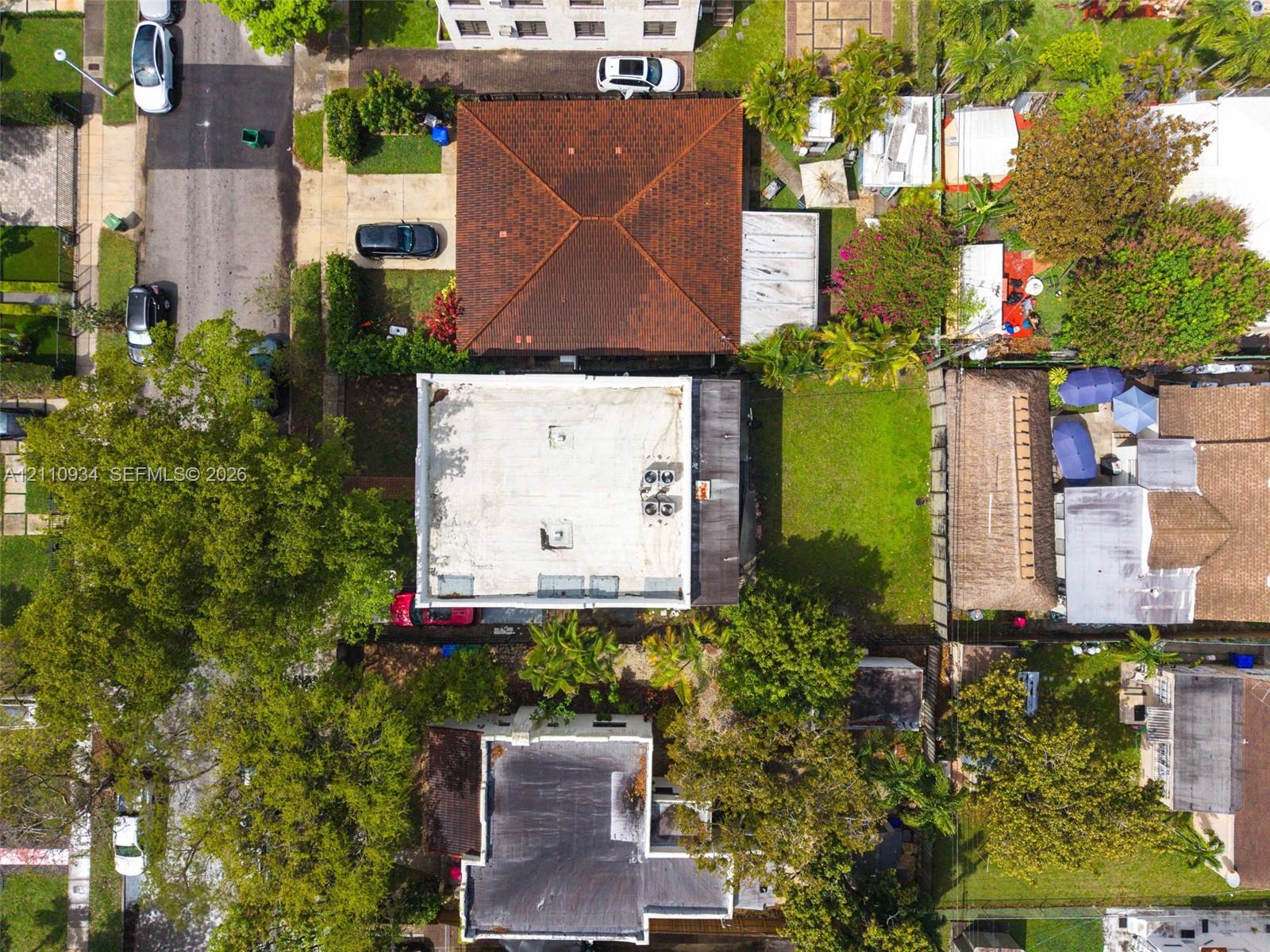 Aerial view of property featuring a flat roofline, integrated HVAC units, and a private grass-covered backyard