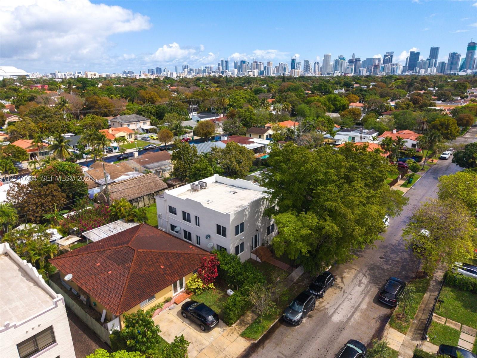 Aerial perspective of a multi-level structure featuring a flat roof, white exterior cladding, and urban skyline backdrop Aerial perspective of a multi-level structure featuring a flat roof, white exterior cladding, and urban skyline backdrop