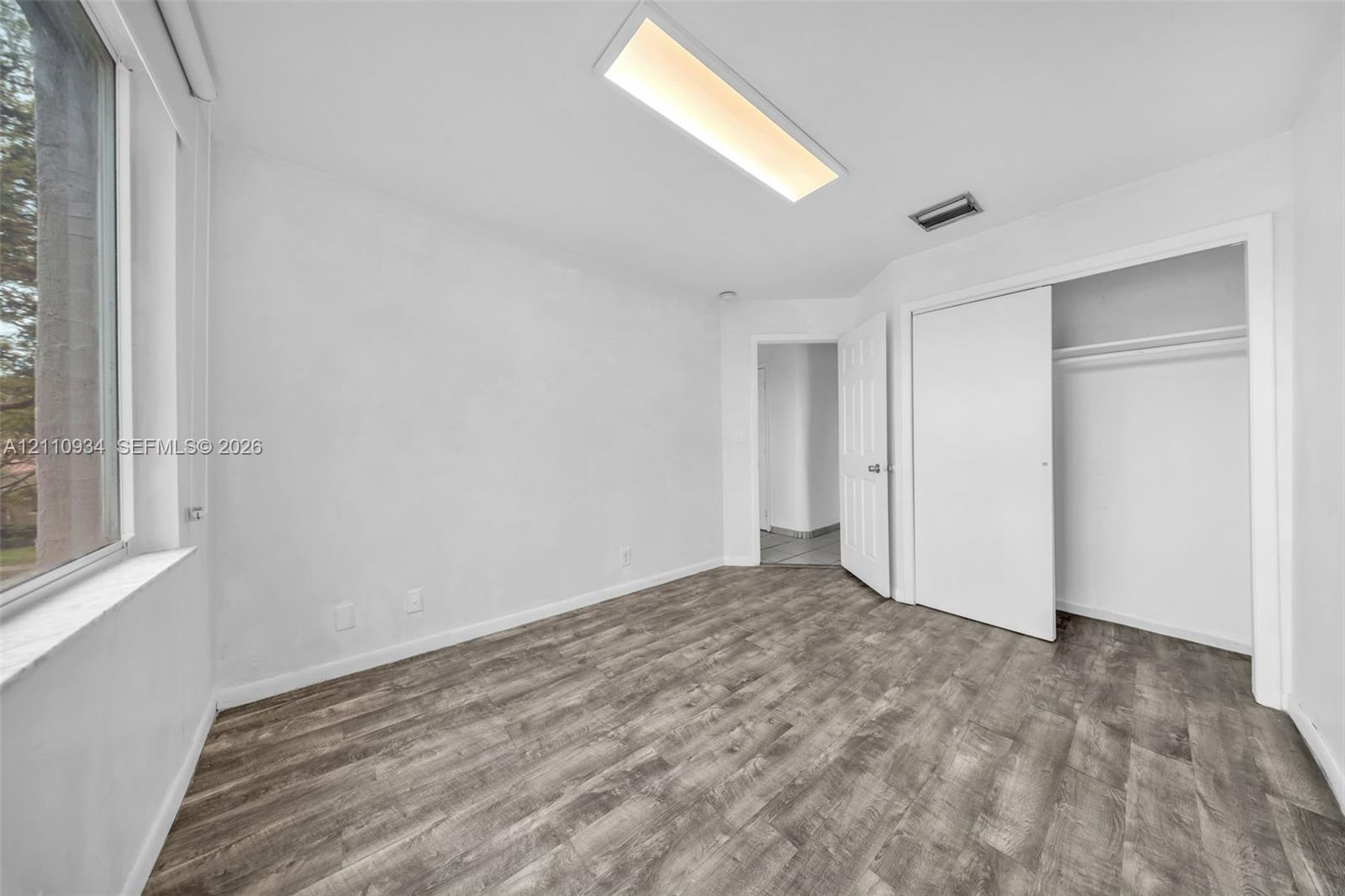 Room featuring wood-finish flooring, recessed rectangular ceiling lighting, and a closet with sliding doors