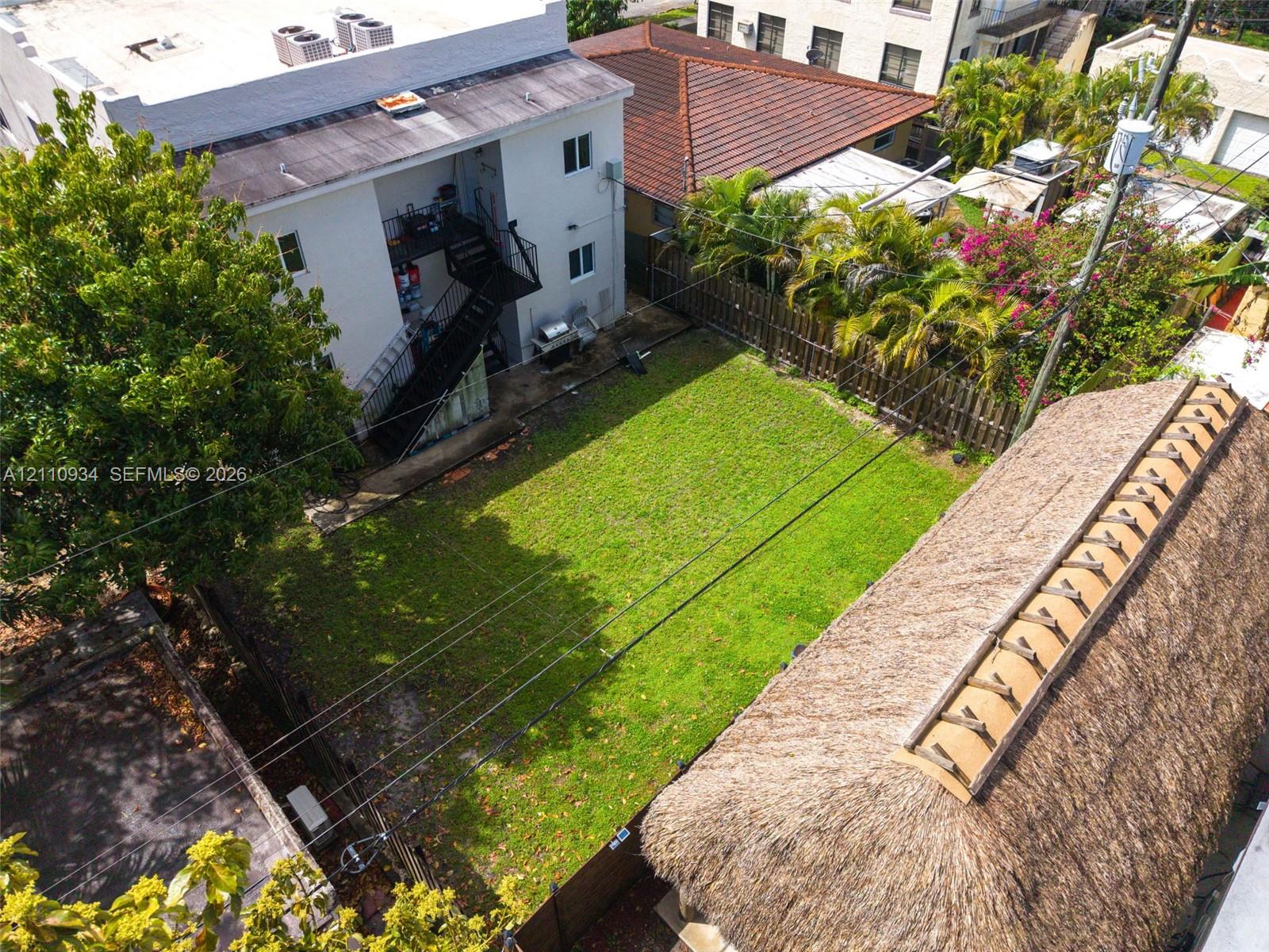 Open green space featuring a manicured lawn, perimeter wood fencing, and mature trees
