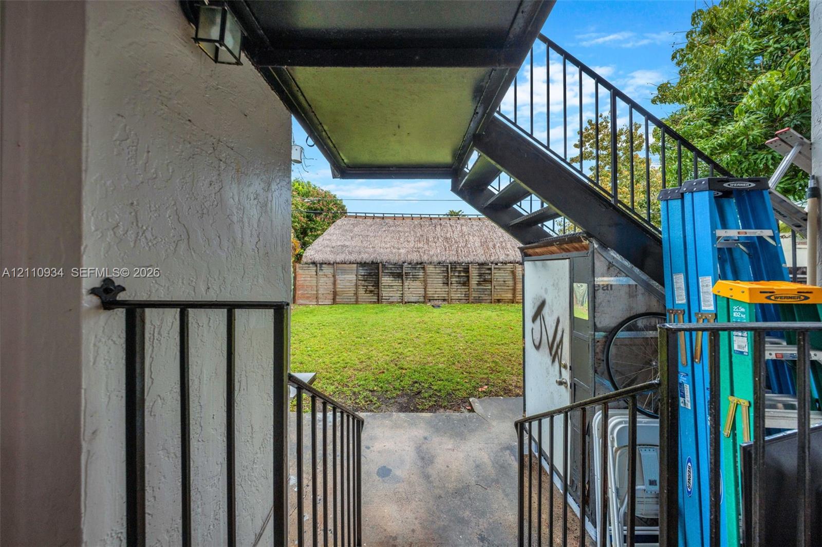 Exterior space featuring metal staircase, concrete surface, and wood-panel perimeter wall