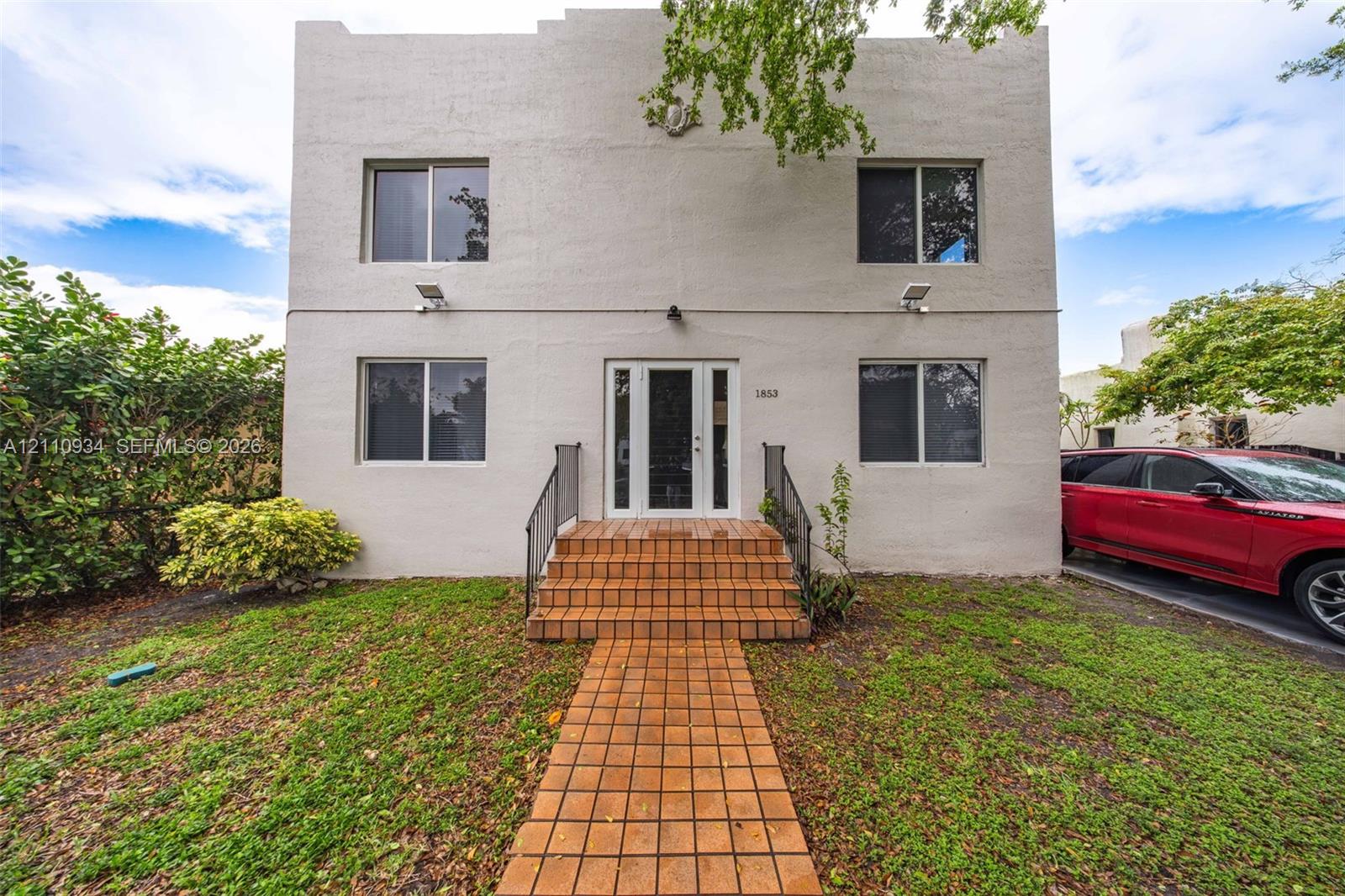 Two-story exterior featuring a stucco facade, stepped roofline, tiled front steps, tiled walkway, and full-light front entry door with sidelights Two-story exterior featuring a stucco facade, stepped roofline, tiled front steps, tiled walkway, and full-light front entry door with sidelights