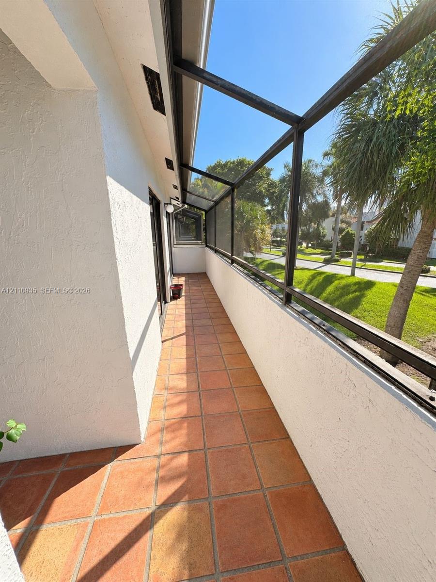 Covered screened porch featuring terracotta tile flooring, stucco wall finish, and metal framing