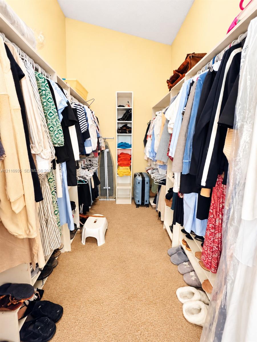 Walk-in closet featuring extensive built-in white shelving, hanging rods, and a vertical multi-tier storage column