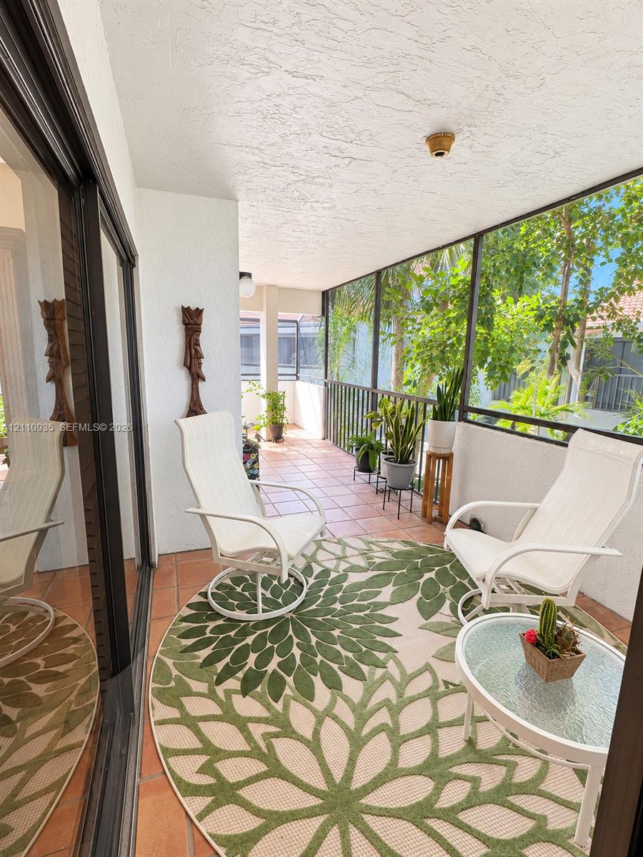 Screened-in balcony featuring tile flooring, metal railings, and sliding glass door entry