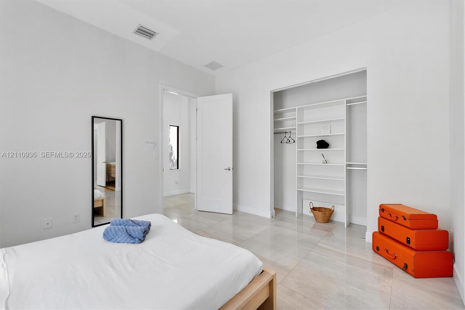 Interior space featuring light-toned tile flooring, high ceilings, and a built-in walk-in closet system with shelving Interior space featuring light-toned tile flooring, high ceilings, and a built-in walk-in closet system with shelving