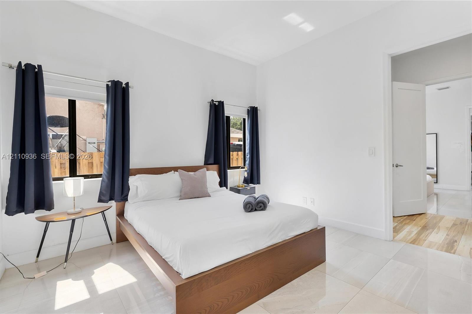 Large-format tile flooring, neutral wall tones, and two windows with black-finish window frames and hardware