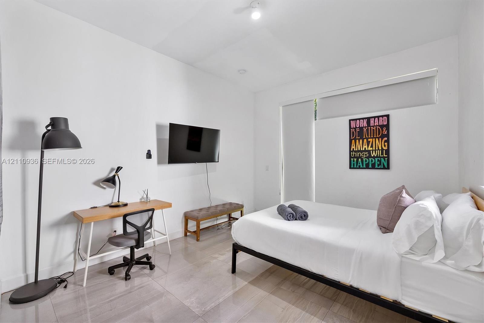 Neutral-toned tile flooring, high ceilings, and floor-to-ceiling roller shades Neutral-toned tile flooring, high ceilings, and floor-to-ceiling roller shades