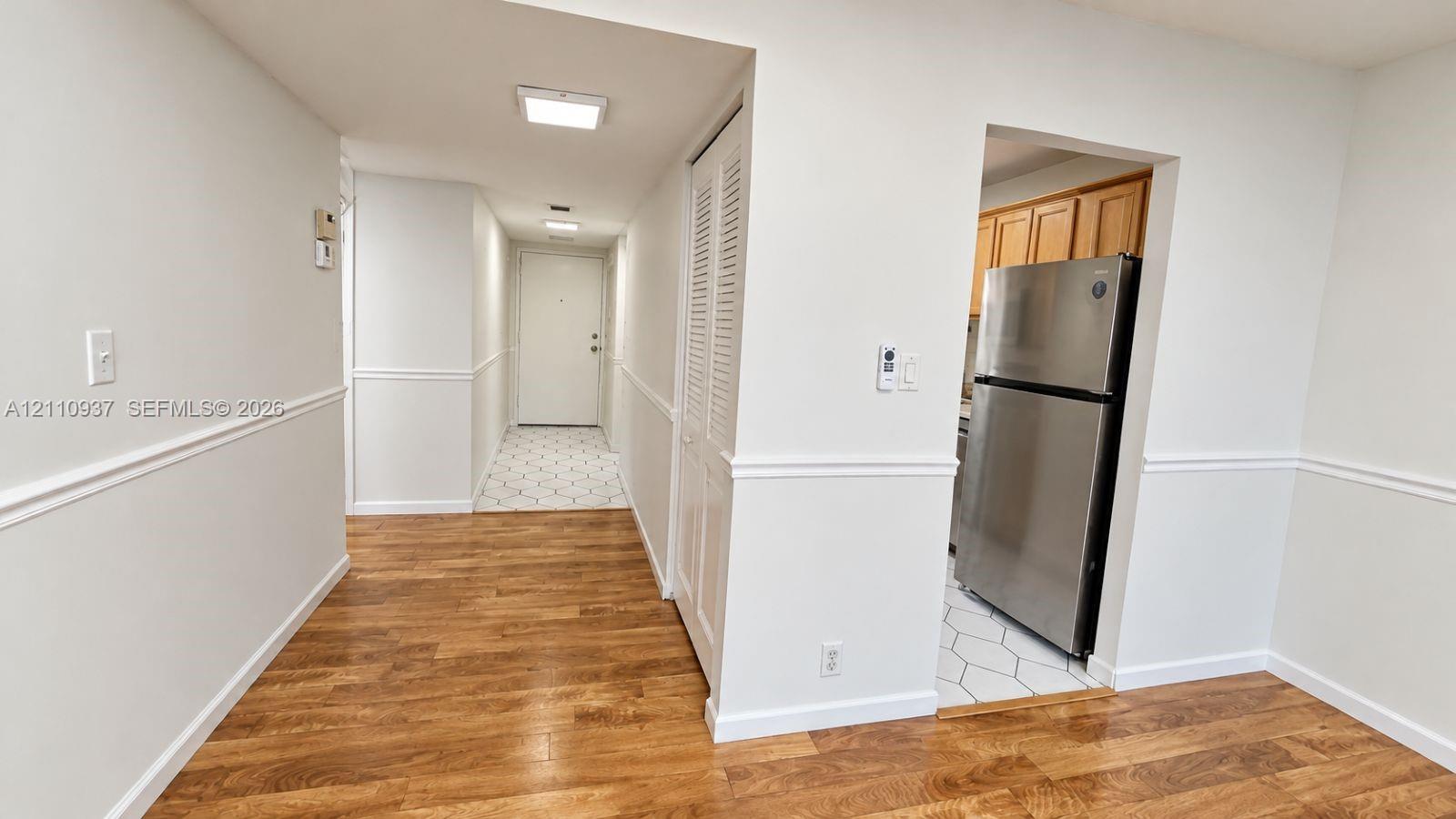 Interior featuring wood-finish flooring, white chair rail molding, louvered closet doors, and stainless steel refrigerator