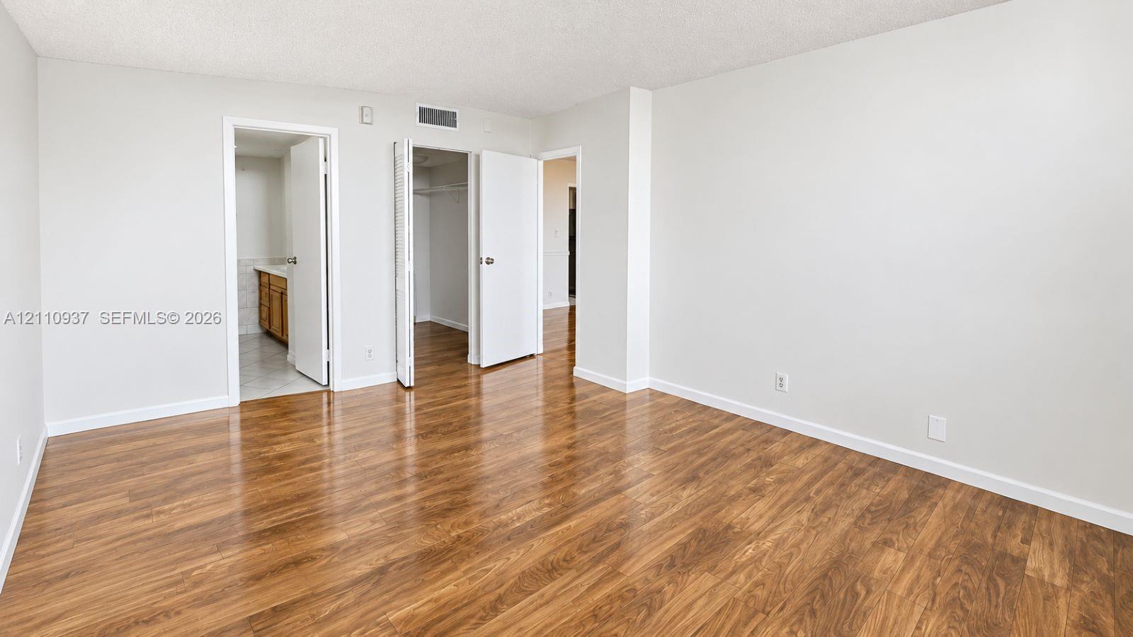 Interior space featuring wood-finish flooring, neutral wall paint, and multiple interior doors with hardware