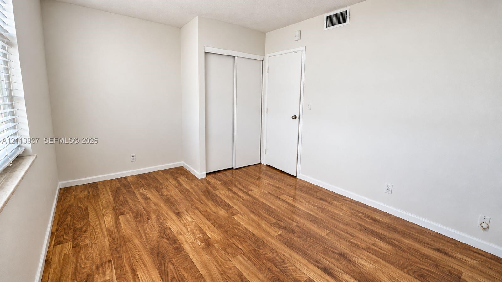 Neutral-toned interior featuring wood-finish flooring, a double-panel sliding closet, and a single-panel interior door