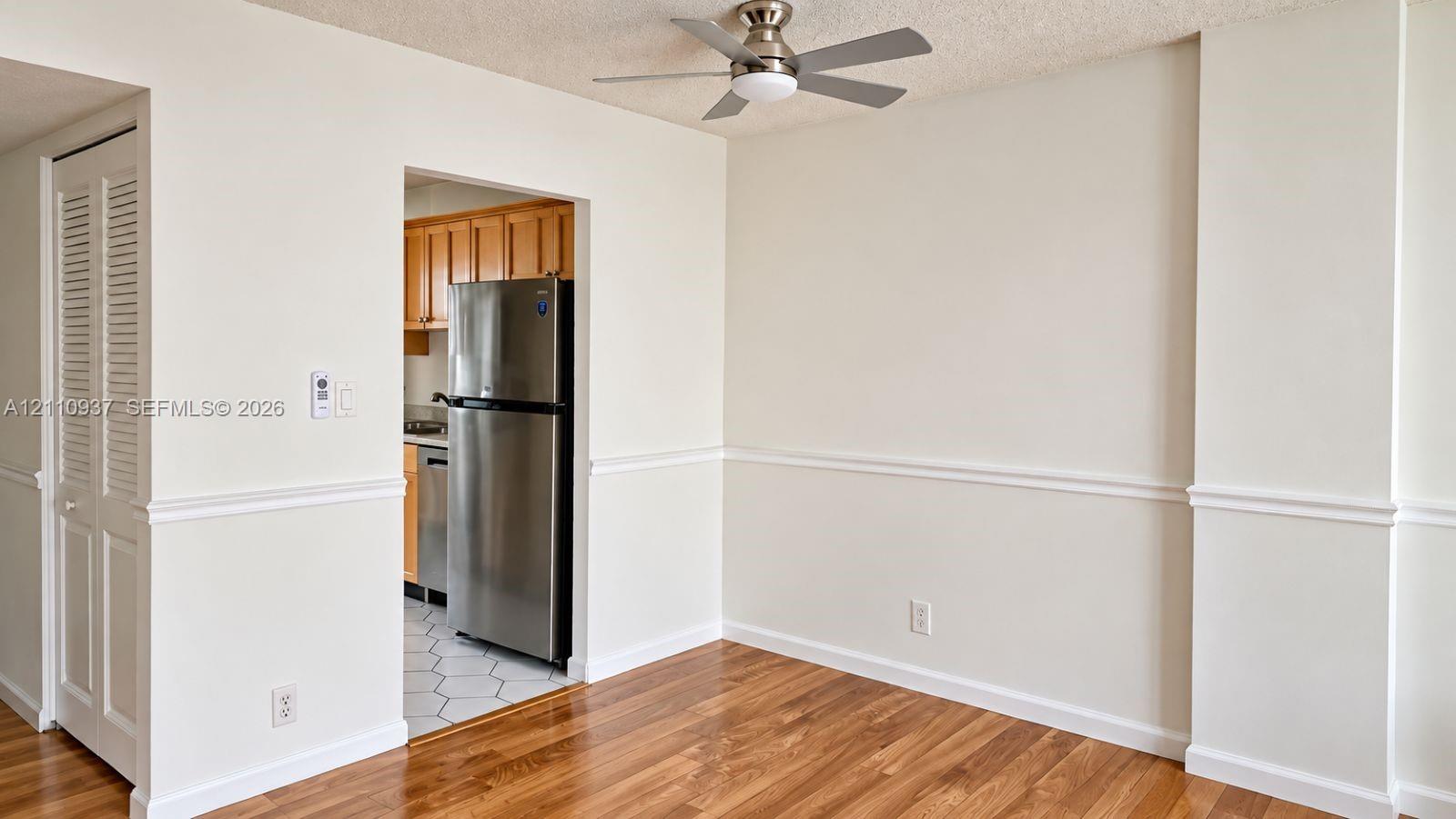 Wood-finish flooring, chair rail molding, ceiling fan with integrated lighting, and louvered closet doors