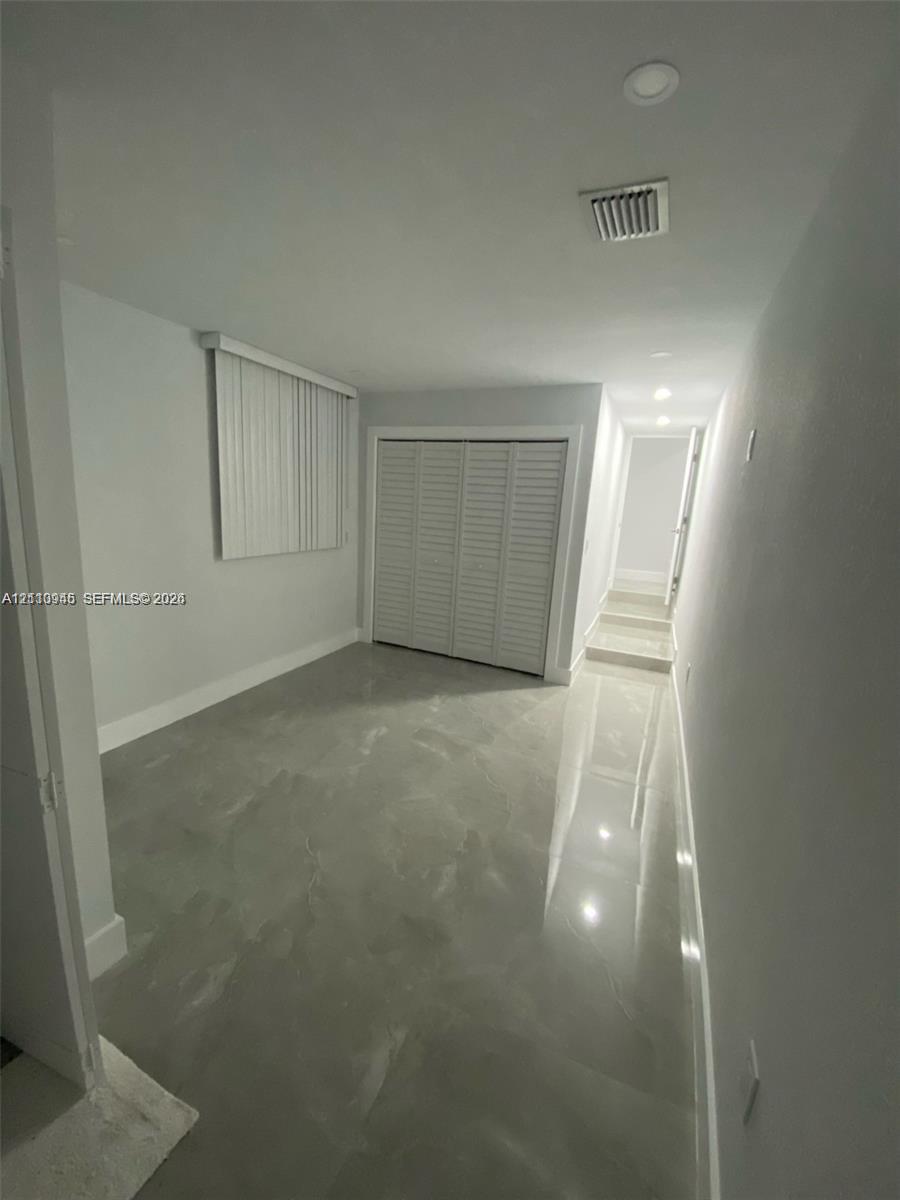Interior space featuring high-gloss tile flooring, recessed ceiling lighting, and a closet with white louvered bifold doors