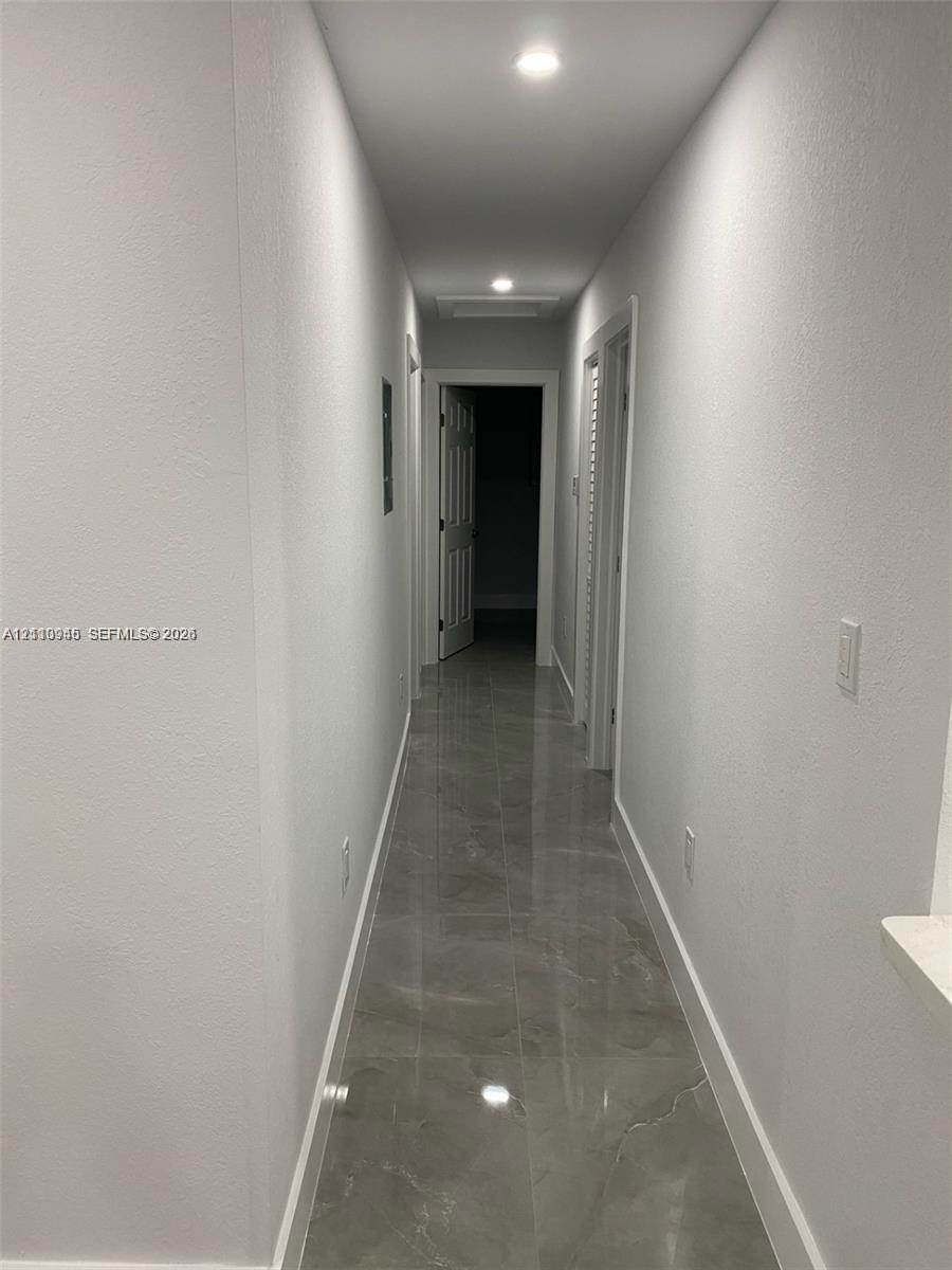 Hallway featuring large-format tile flooring, recessed ceiling lighting, and crisp white wall finishes