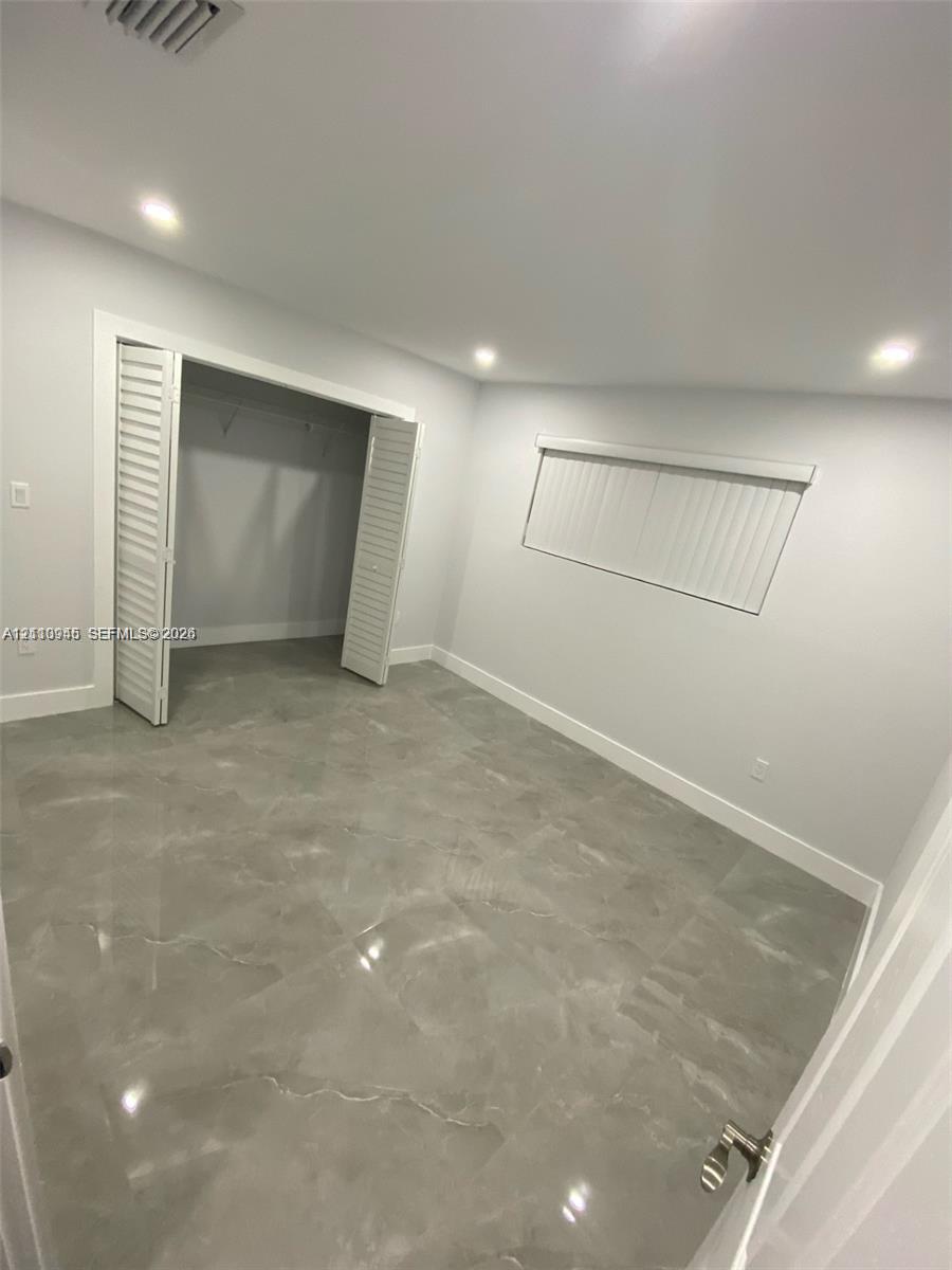 Room featuring high-gloss polished stone-style tile flooring, recessed ceiling lighting, and a bi-fold door closet