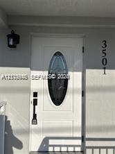 Entryway featuring a white door with an oval glass insert, vertical-mount house numbers, and a classic-style wall sconce
