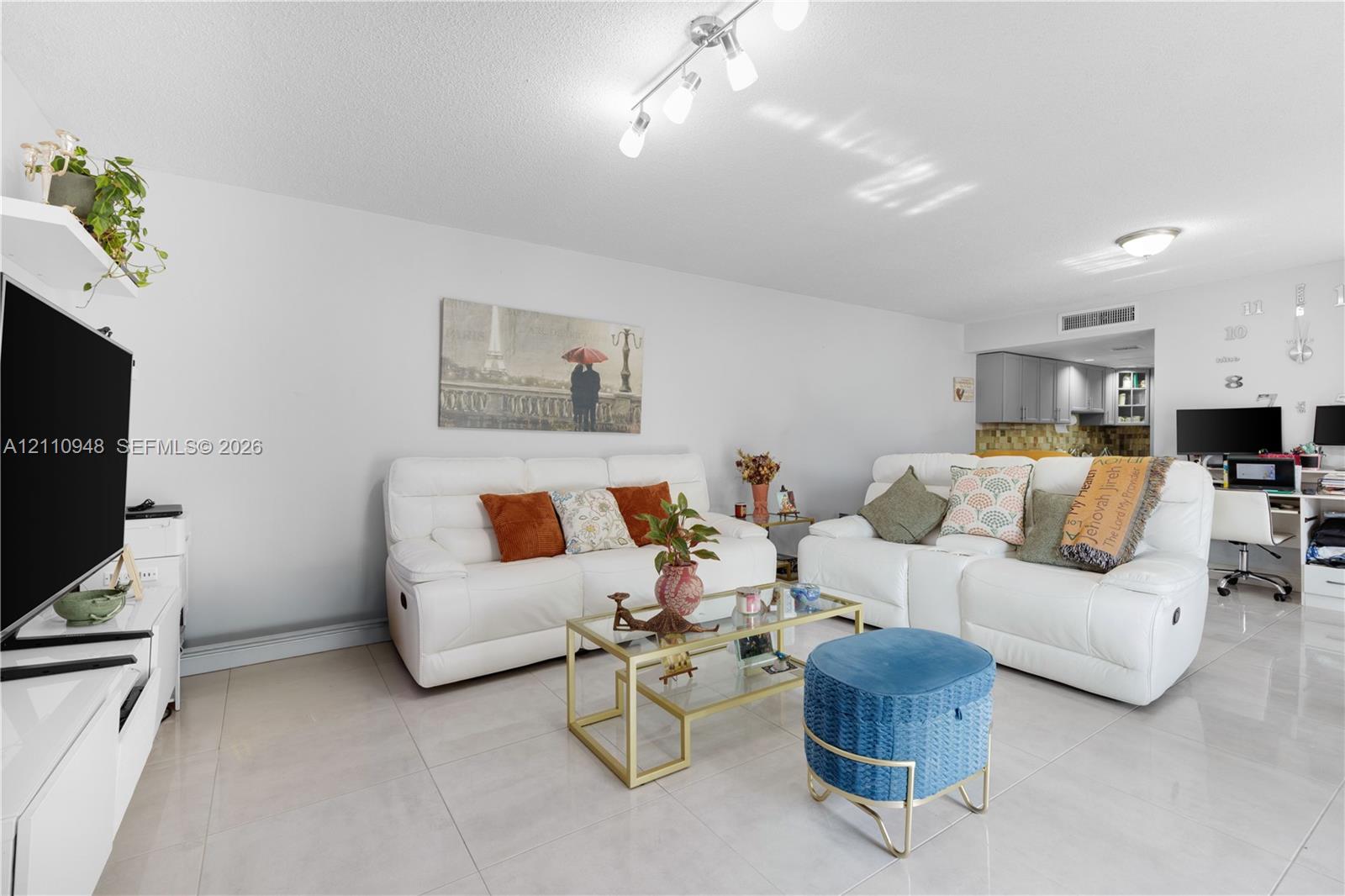 Living area featuring polished tile flooring, multi-directional track lighting, and a neutral color palette Living area featuring polished tile flooring, multi-directional track lighting, and a neutral color palette