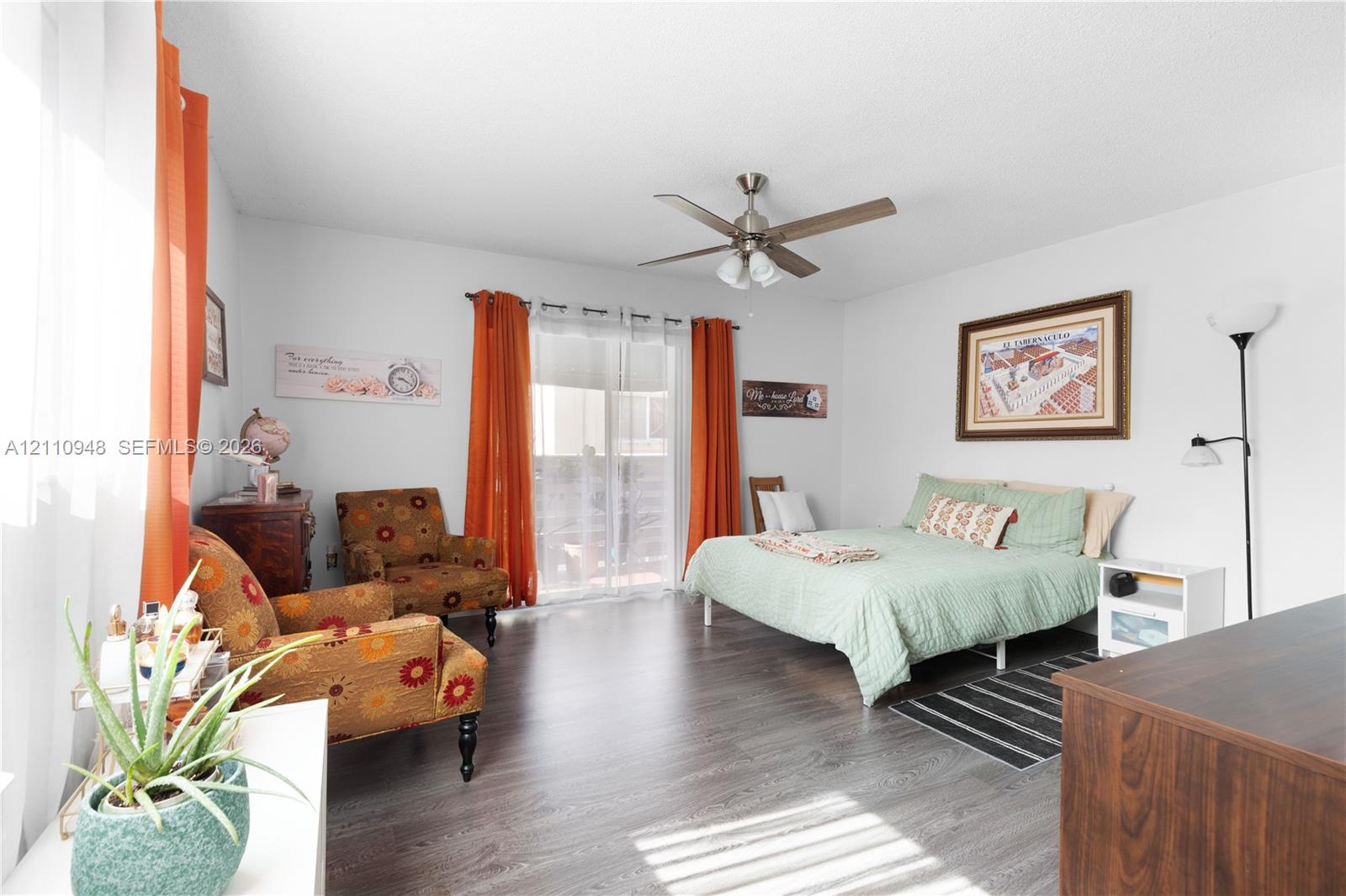 Wood-finish flooring, ceiling fan with integrated lighting, and glass sliding doors providing access to the exterior