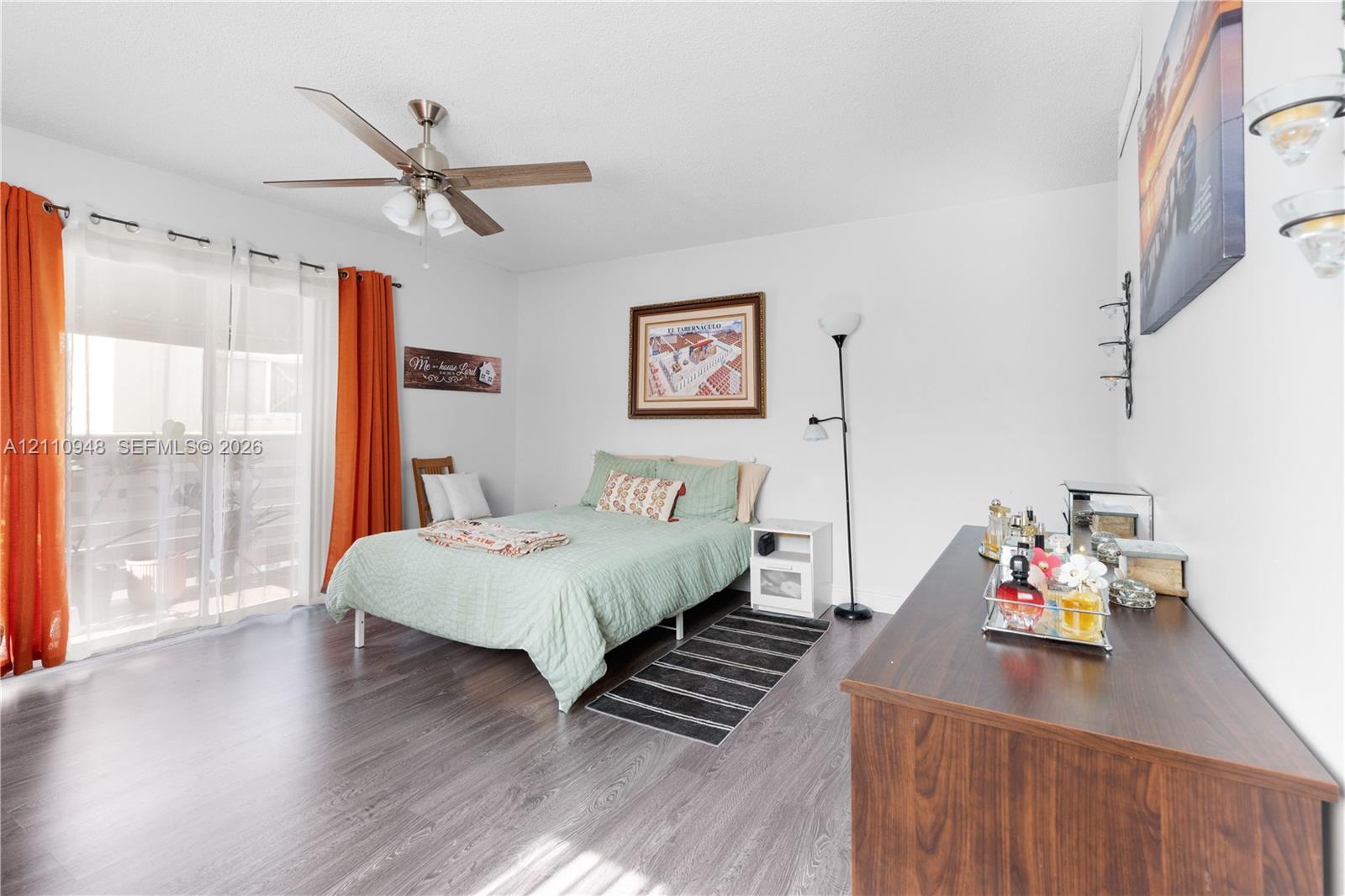 Wood-finish flooring, sliding glass patio doors, and a ceiling fan with integrated lighting