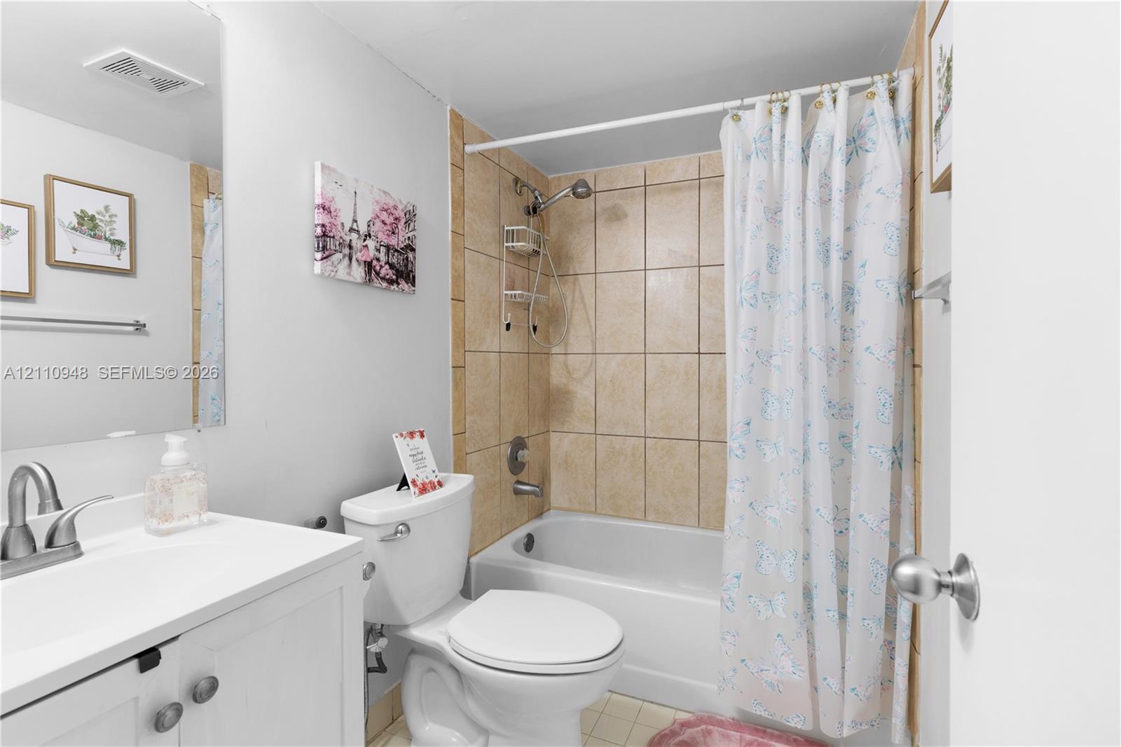 White vanity cabinet with an integrated sink and brushed-nickel faucet, wall-mounted mirror, and a bathtub with full-height tile surround