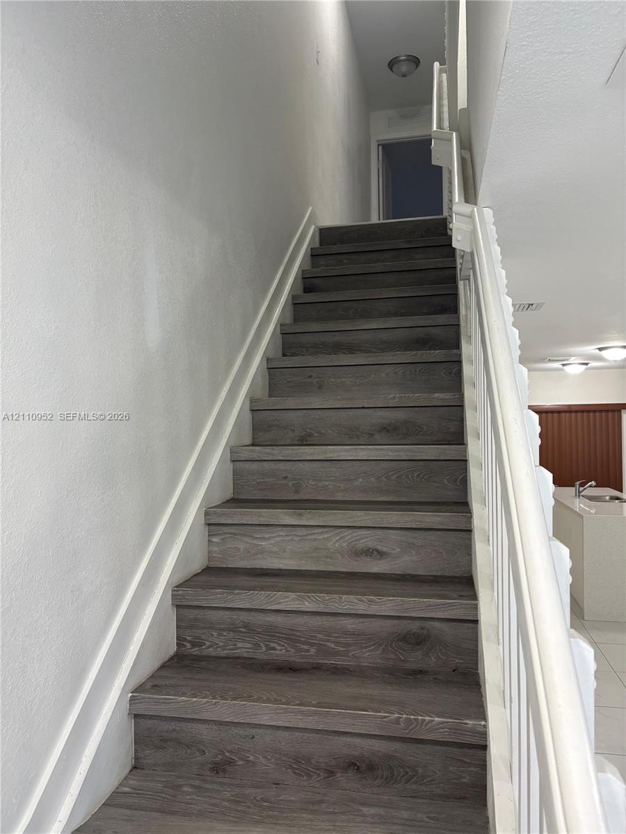 Staircase featuring wood-finish treads, a white handrail, white balusters, and recessed ceiling lighting