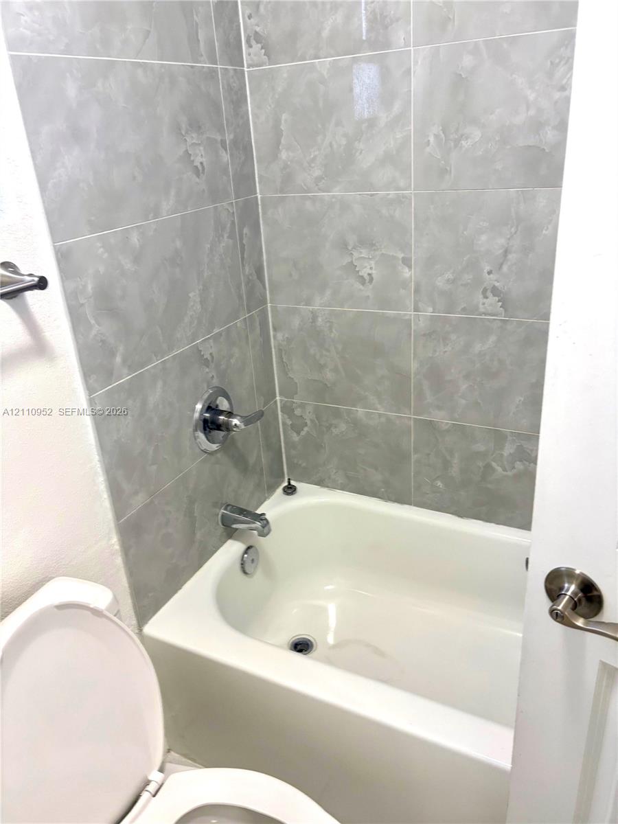 Full-height ceramic tile tub surround, integrated porcelain bathtub, and polished chrome hardware
