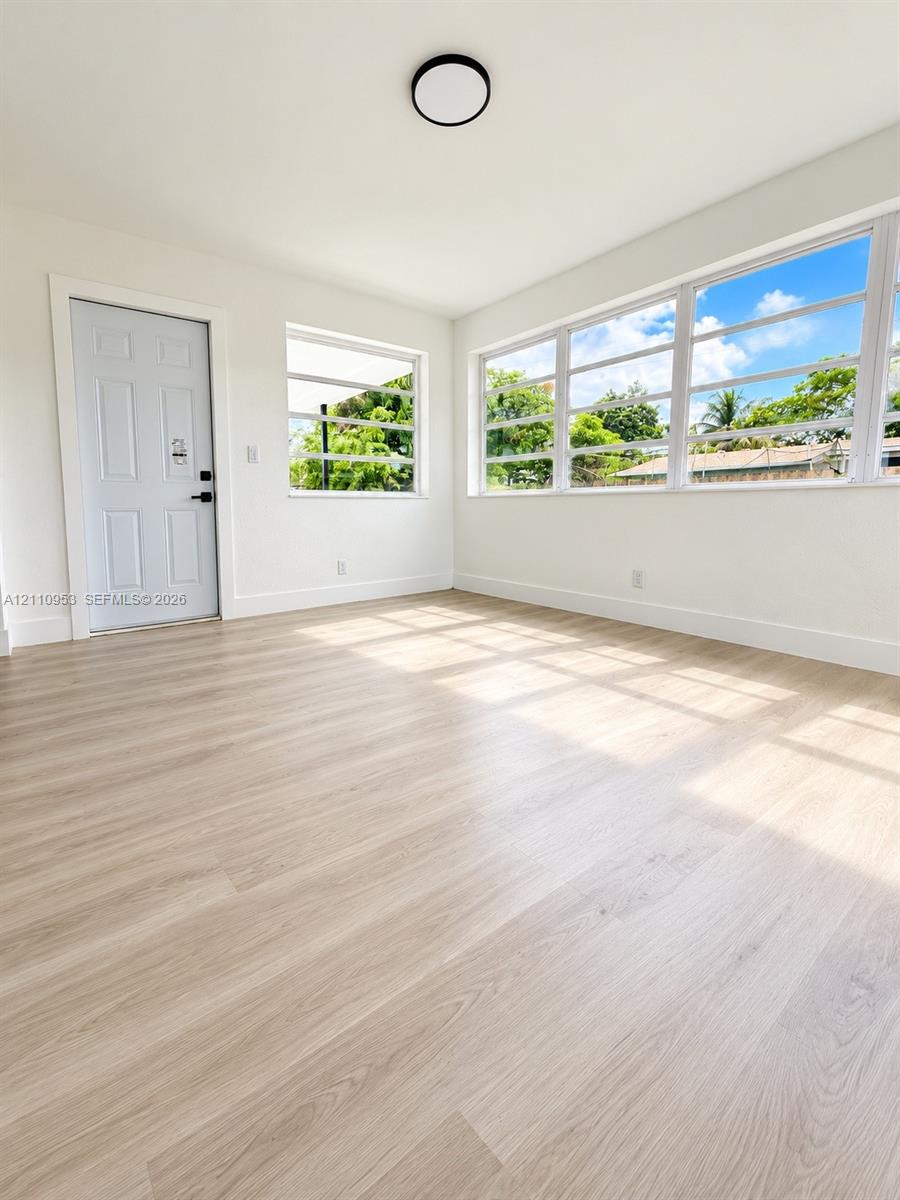 Neutral walls and wood-finish flooring, expansive horizontal sliding windows, and a flush-mount circular lighting fixture