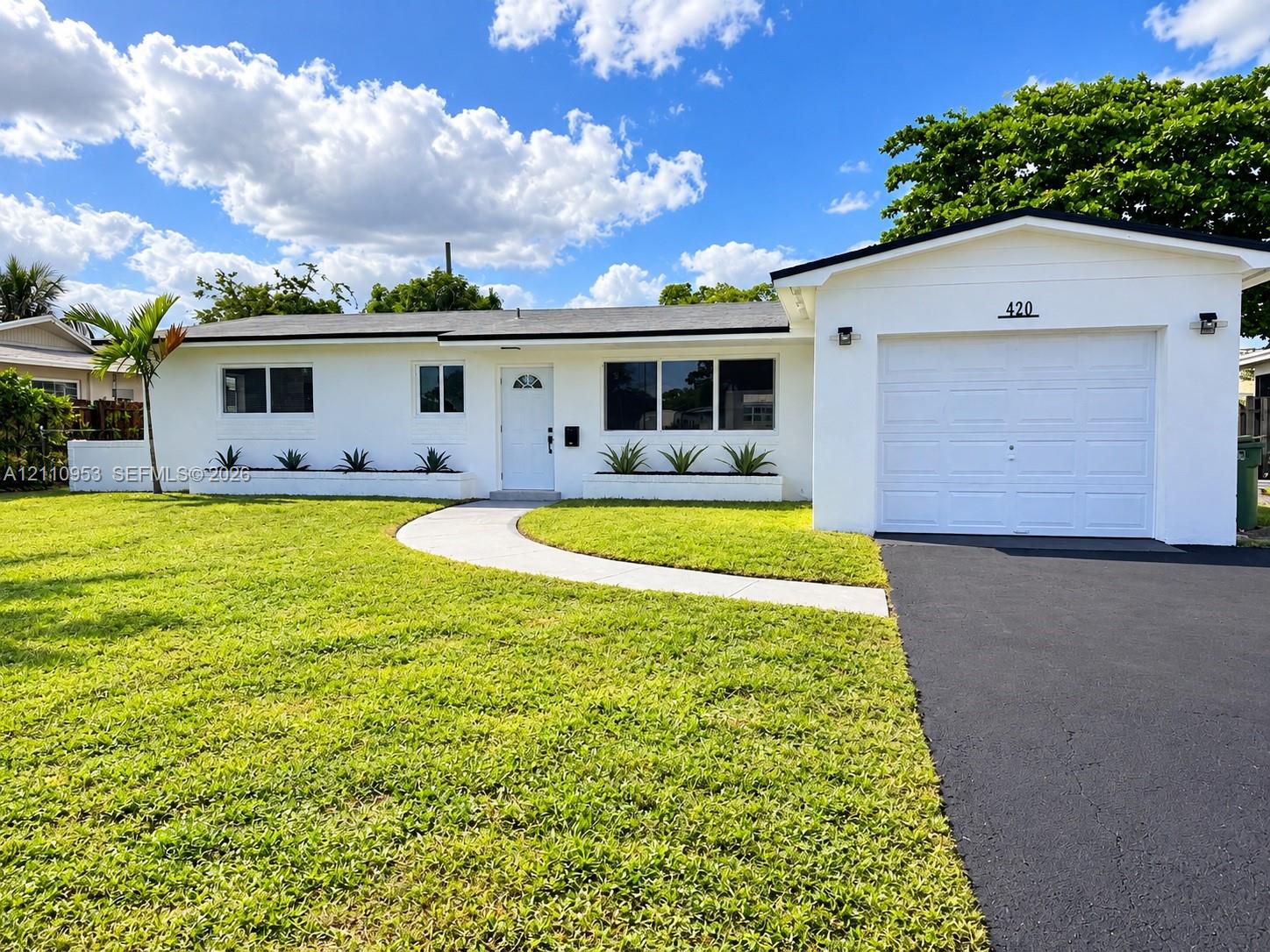 Single-story exterior featuring a crisp white finish, integrated concrete planter beds, a paved walkway, and an attached garage with an asphalt driveway Single-story exterior featuring a crisp white finish, integrated concrete planter beds, a paved walkway, and an attached garage with an asphalt driveway