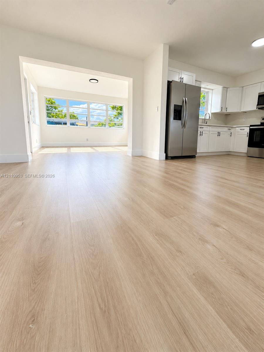 Wood-finish flooring, white shaker-style cabinetry, stainless steel appliances, and multi-pane windows Wood-finish flooring, white shaker-style cabinetry, stainless steel appliances, and multi-pane windows