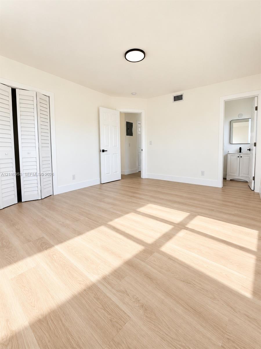 Interior space featuring wood-finish flooring, white louvered bi-fold closet doors, and a ceiling-mounted LED fixture