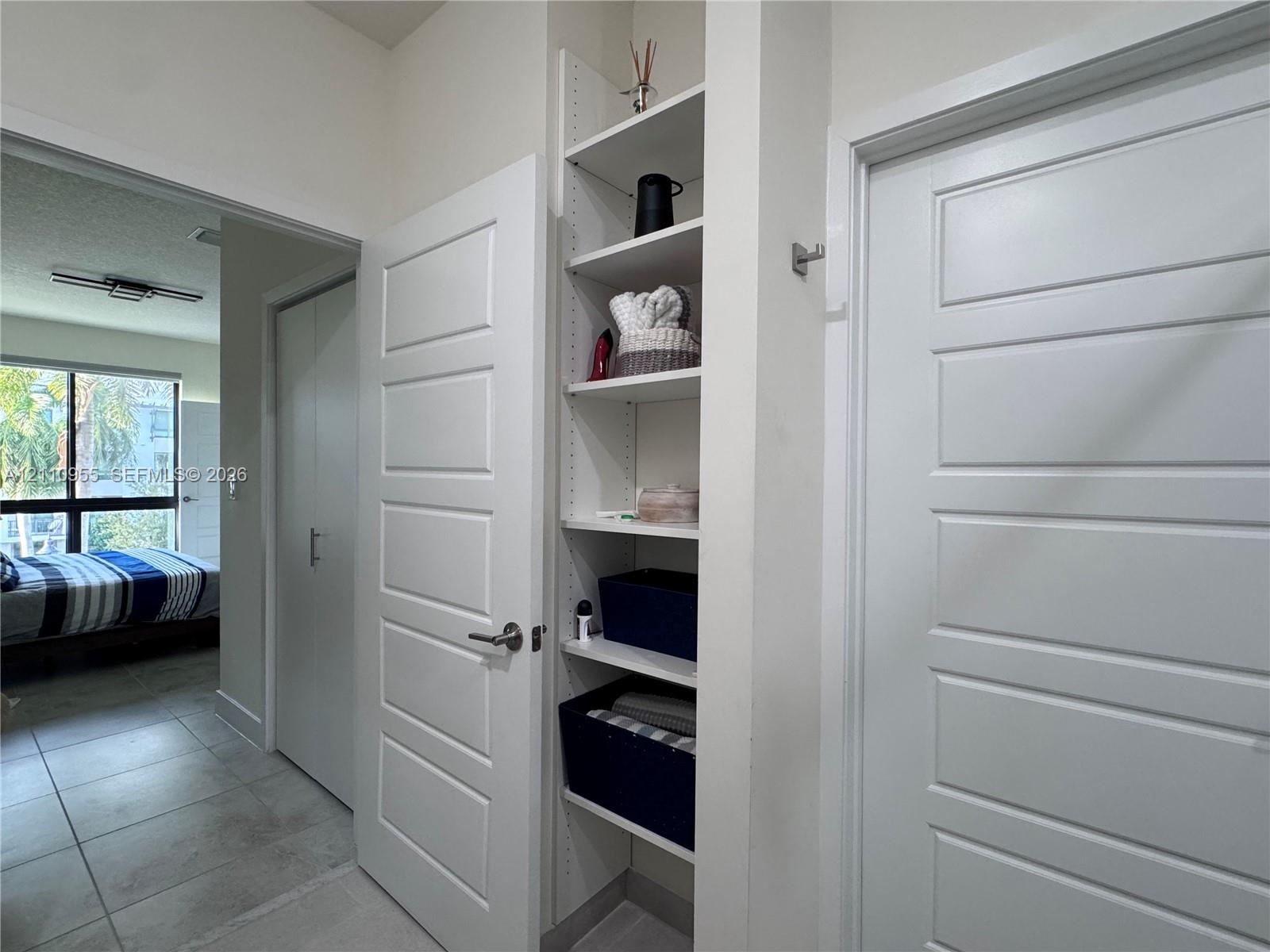 Built-in white shelving unit, four-panel interior doors, and tile flooring