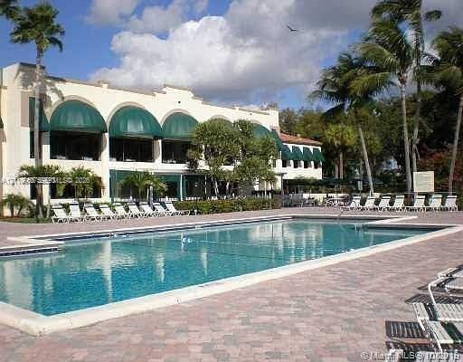Rectangular swimming pool with stone-paver decking and mature palm trees