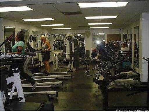 Fitness center featuring drop-ceiling panels, recessed fluorescent lighting, and wall-to-wall mirrors