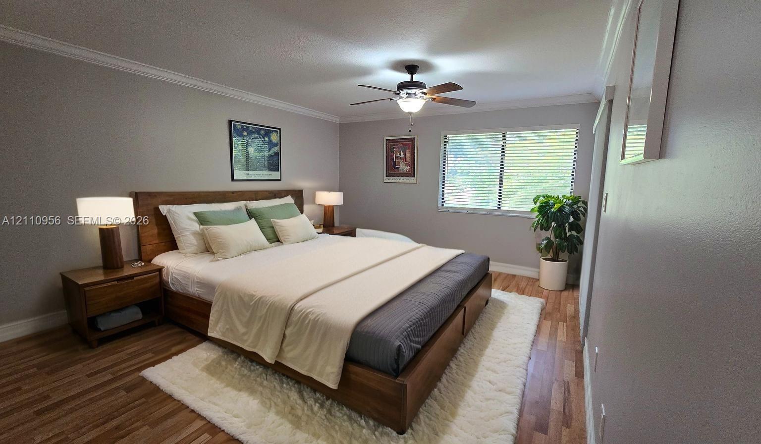Room featuring wood-finish flooring, crown molding, a ceiling fan with integrated lighting, and horizontal window blinds