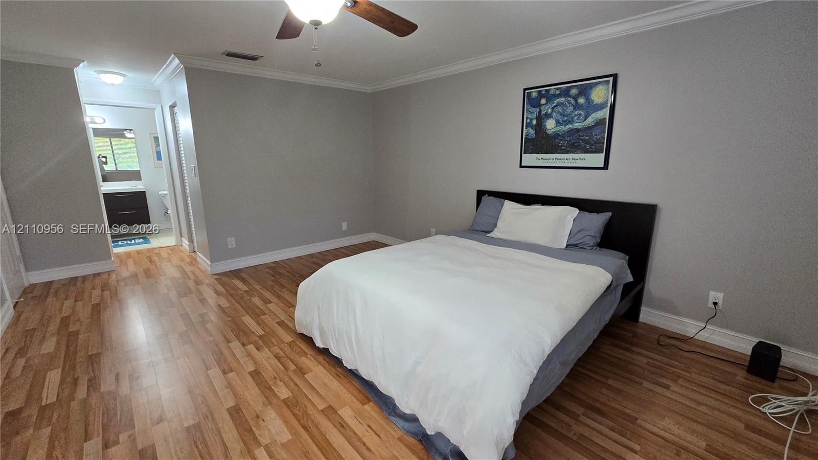Wood-finish flooring, neutral wall tones, crown molding, and a ceiling fan with integrated lighting