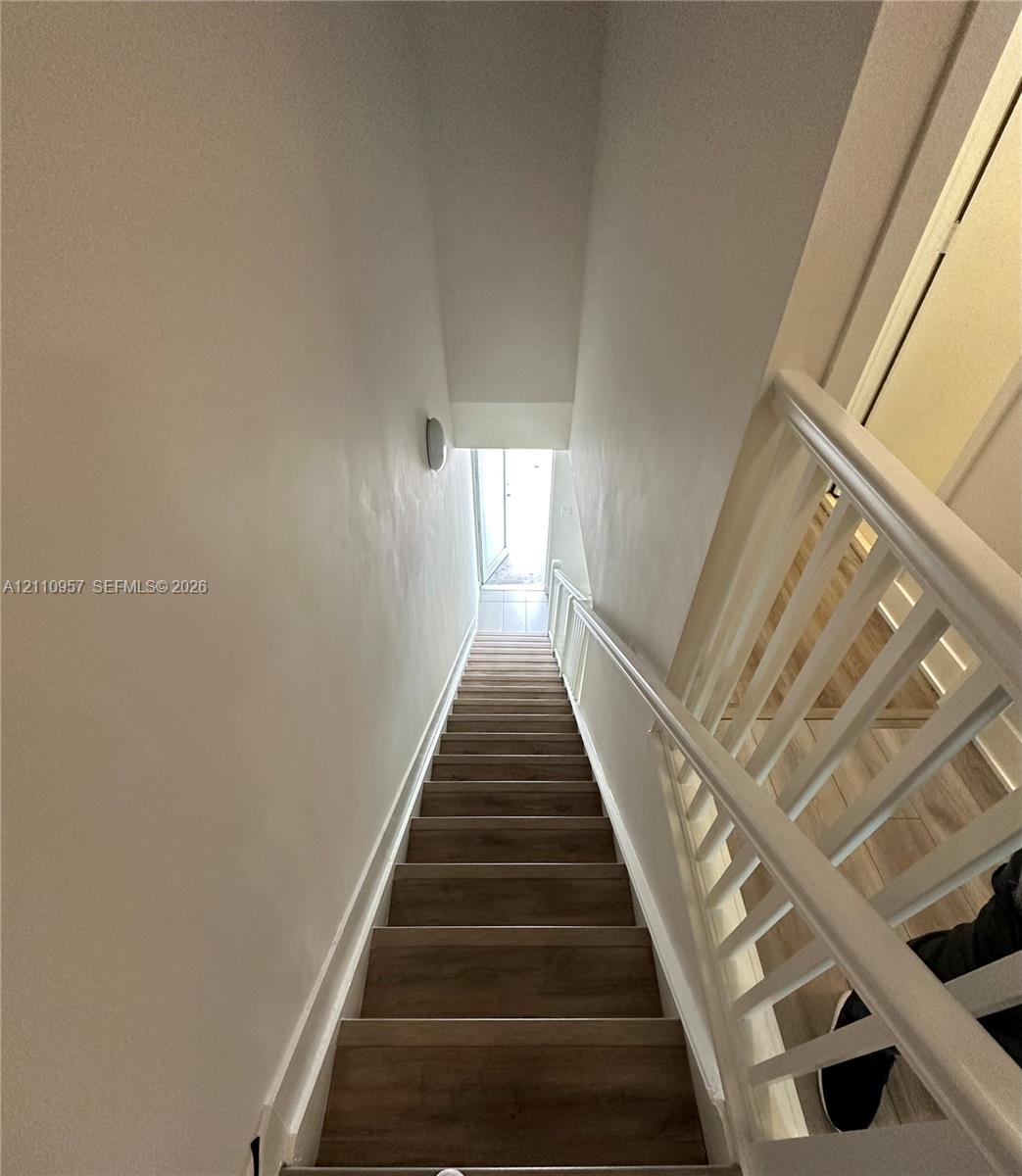 Staircase featuring wood-finish treads and white painted handrails with vertical balusters