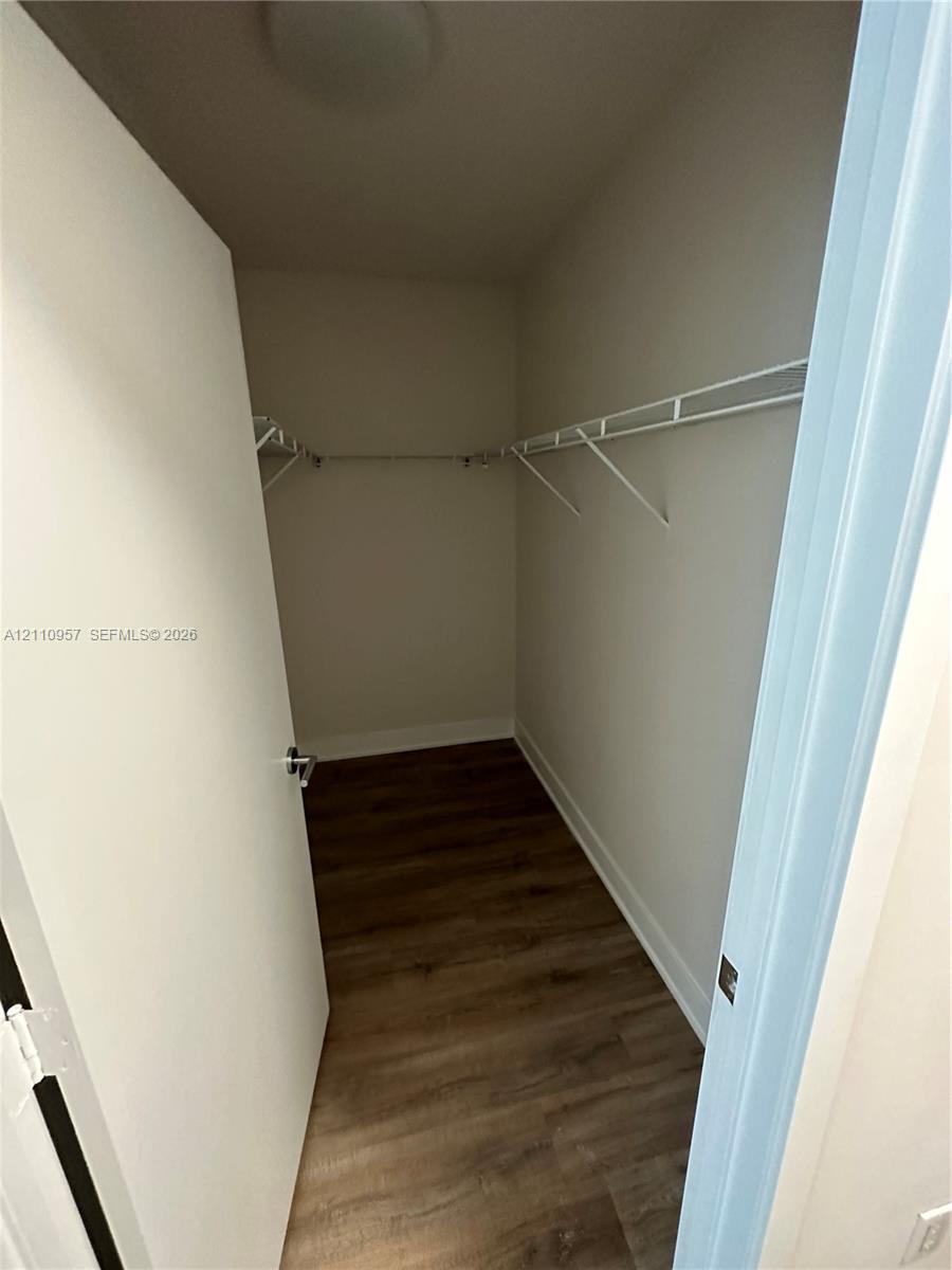 Walk-in storage space featuring wood-finish flooring and wall-mounted wire shelving