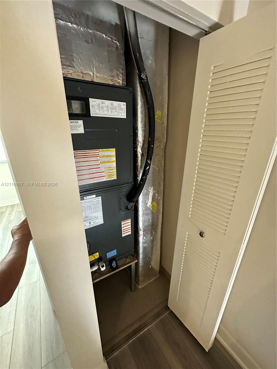 Mechanical closet featuring a vertical furnace unit with attached insulated ductwork and a louvered bi-fold door
