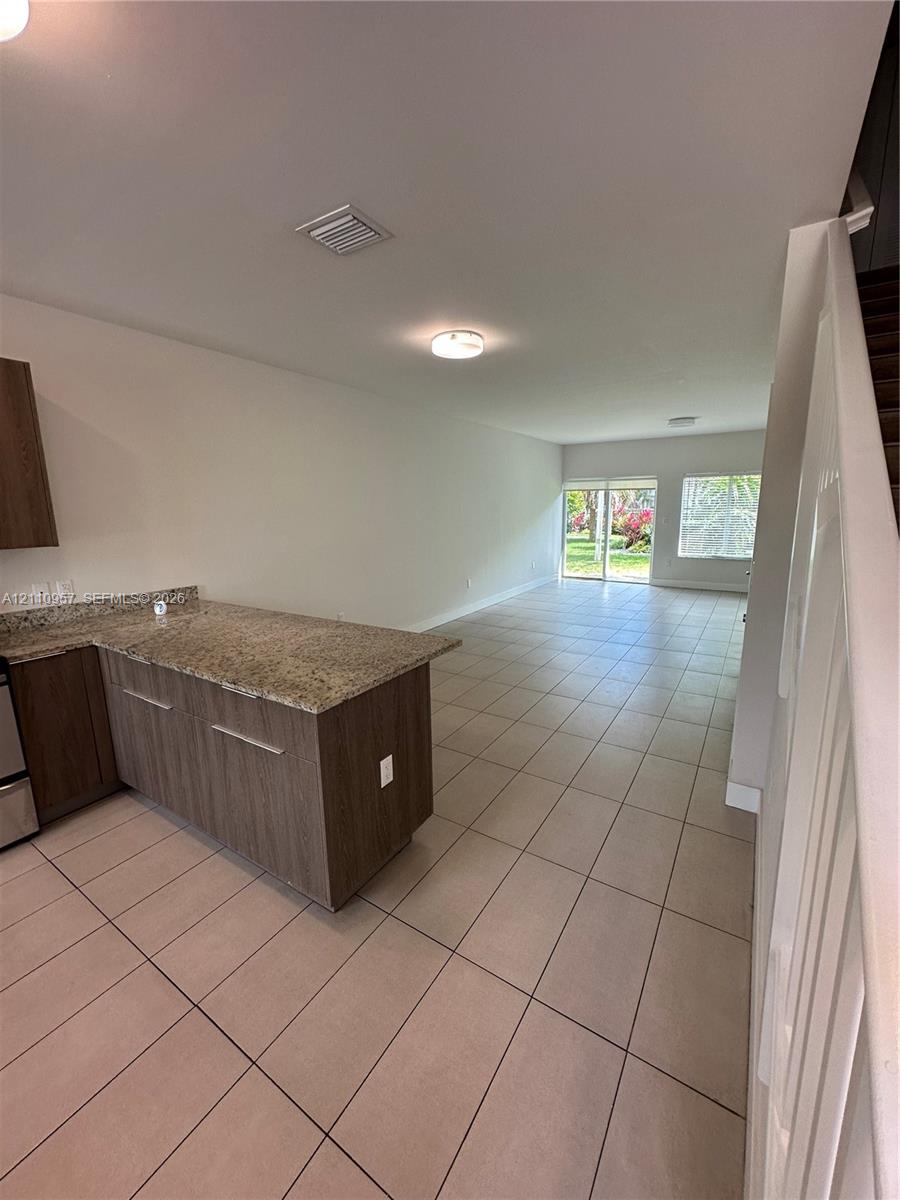 Kitchen featuring flat-panel cabinetry, stone-surface countertops, tile flooring, and sliding glass doors