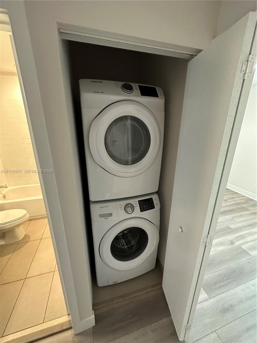 Built-in laundry closet featuring a stacked white front-load washer and dryer