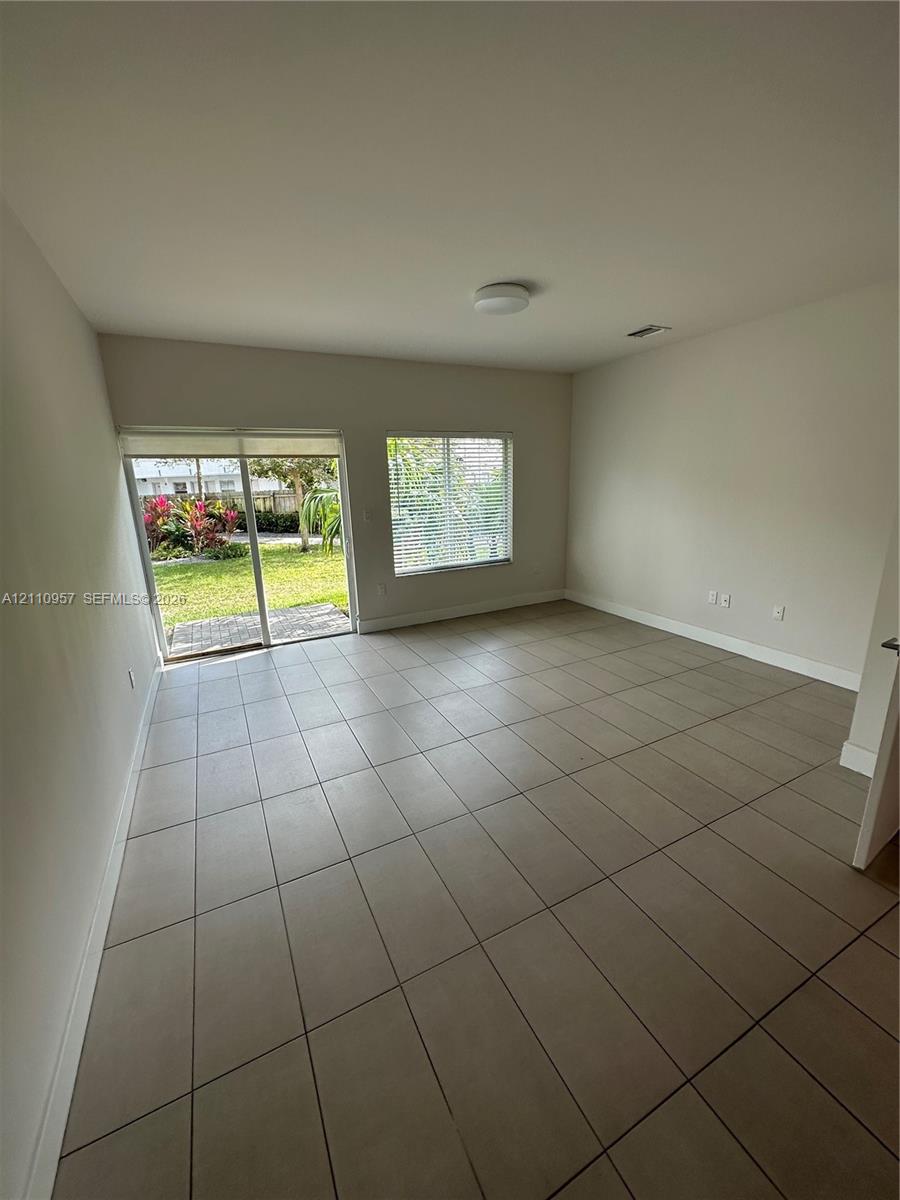 Neutral-toned tile flooring, sliding glass door, and large window with exterior exposure