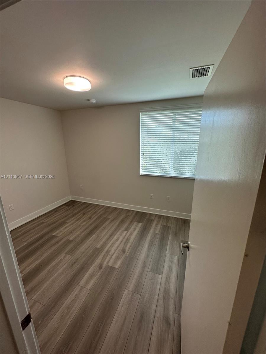 Room featuring wood-finish flooring, neutral wall paint, and a horizontal blind window treatment