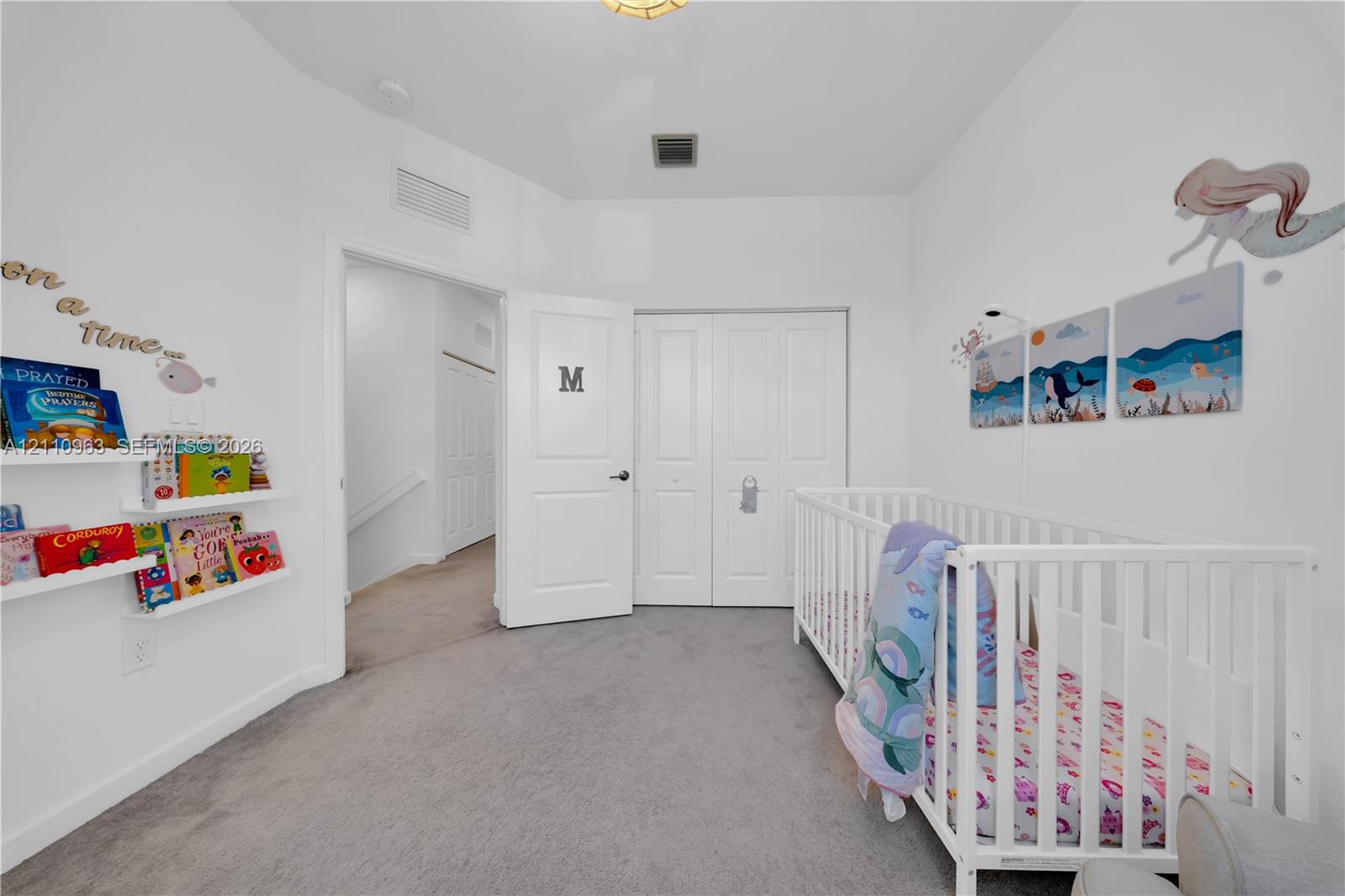 Interior room featuring wall-to-wall carpeting, white two-panel interior doors, built-in floating wall shelving, and a double-door closet