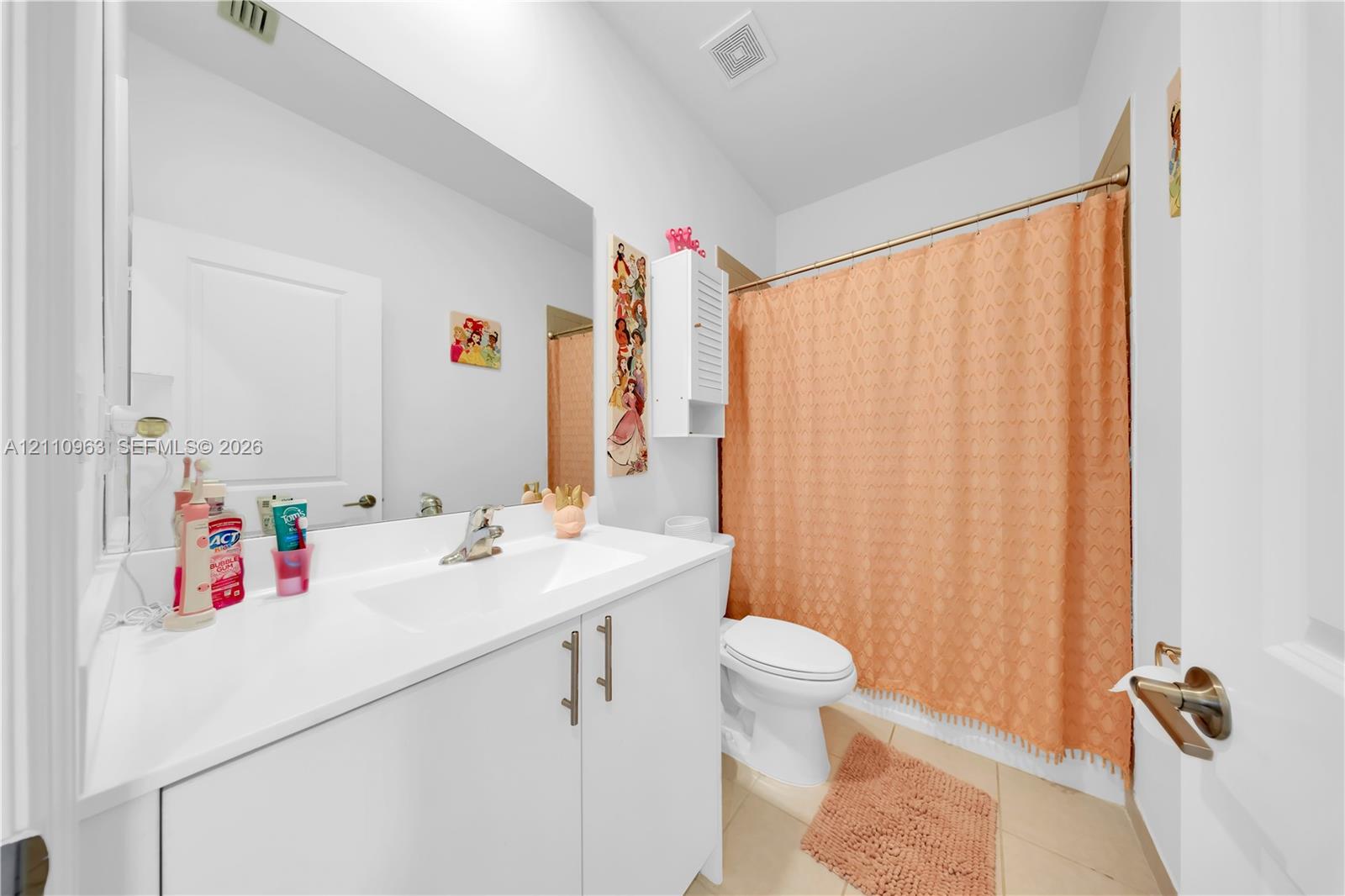 Bathroom featuring a white vanity cabinet with a solid surface countertop, an integrated sink, a full-width wall mirror, and a tub-shower combination with a shower rod