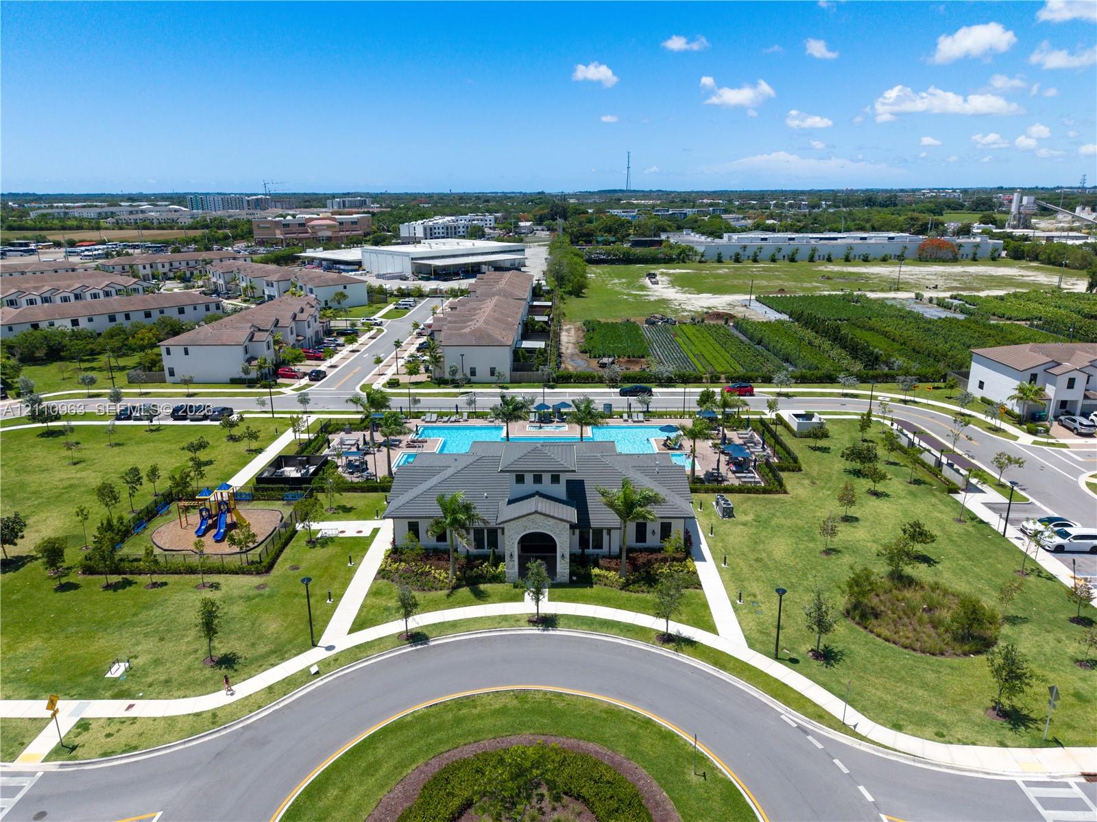 Community clubhouse featuring a swimming pool, surrounding sun deck, and a dedicated playground area situated within landscaped grounds