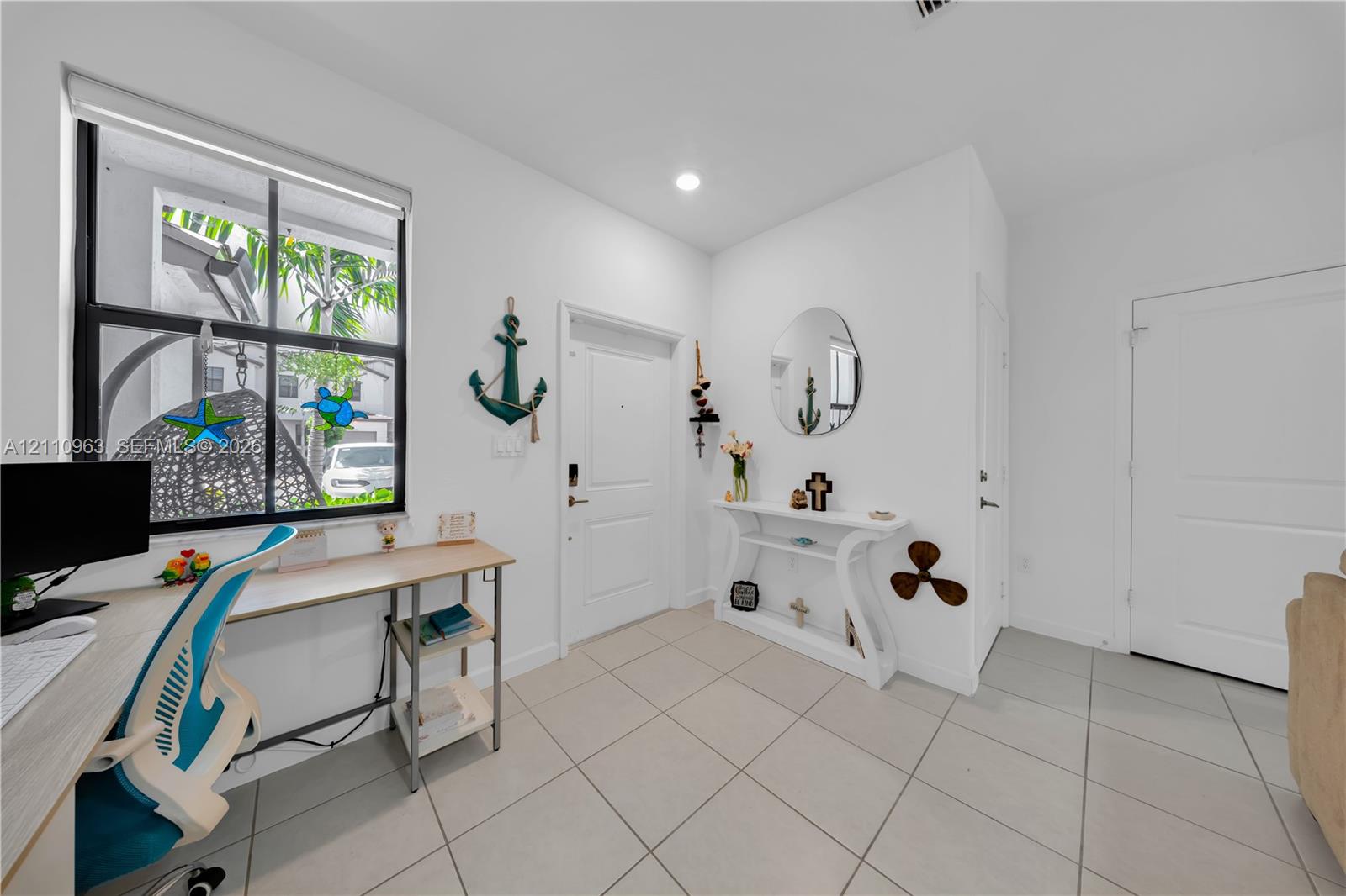 Neutral tile flooring, large multi-pane window, recessed lighting, and white interior doors