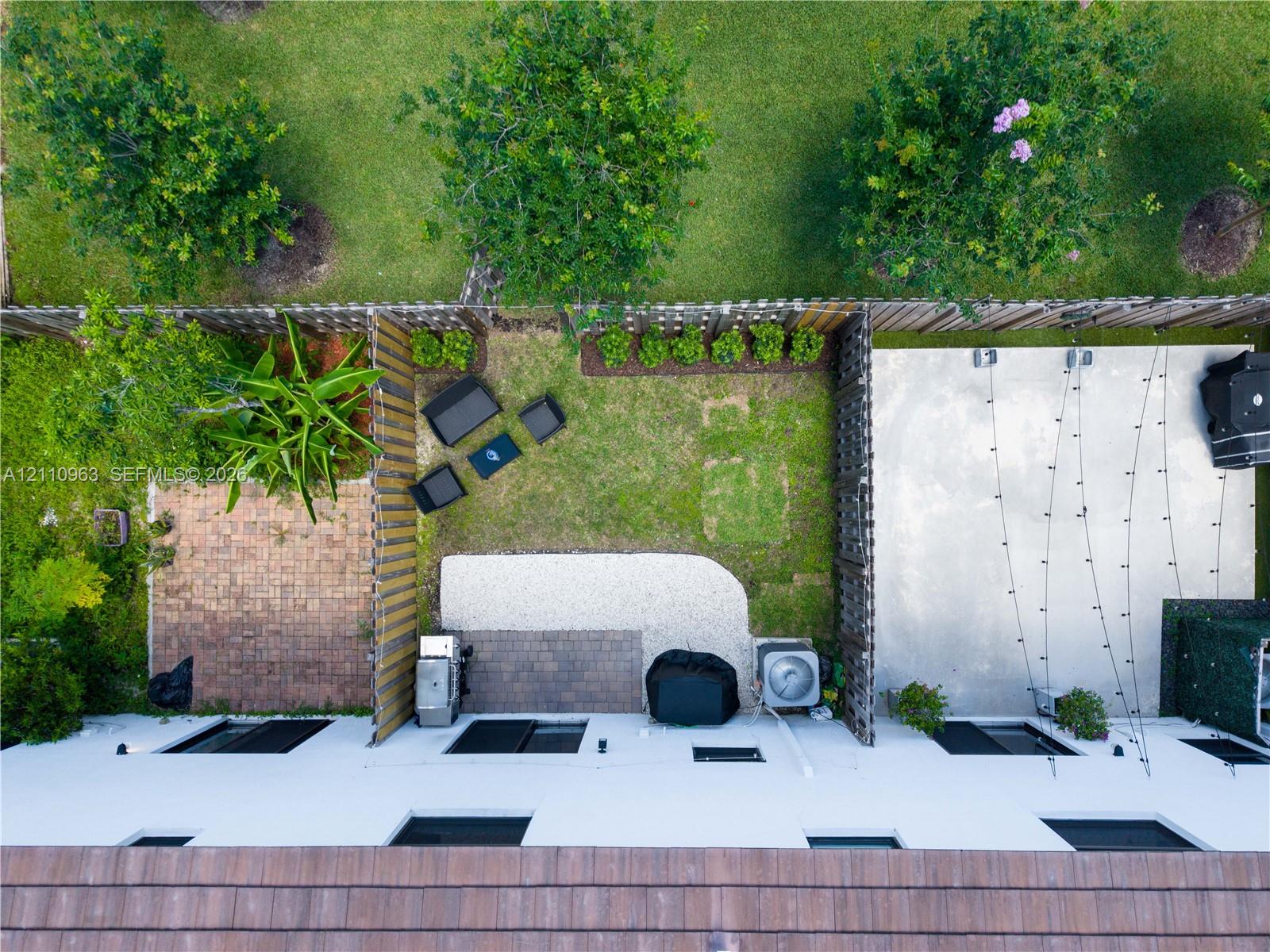 Rear outdoor space featuring a paved patio, gravel ground cover, manicured lawn, and privacy fencing