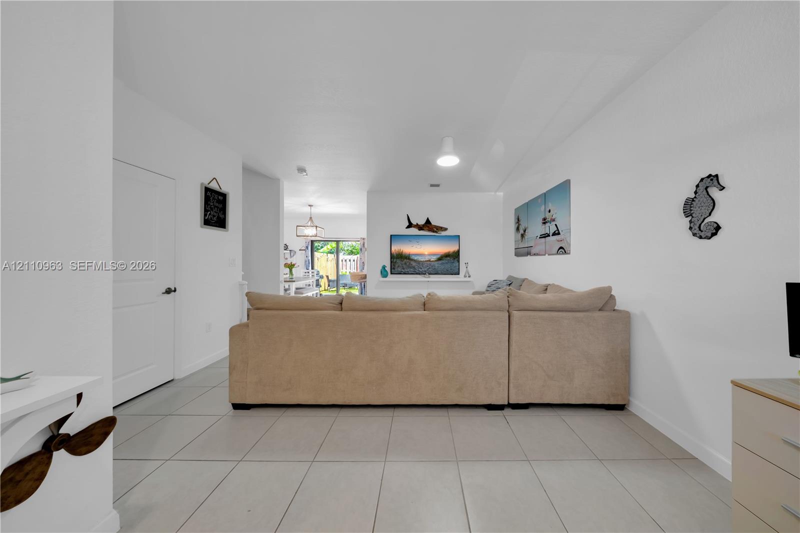 Open-concept interior featuring large-format neutral floor tile, a recessed wall niche, and sliding glass doors