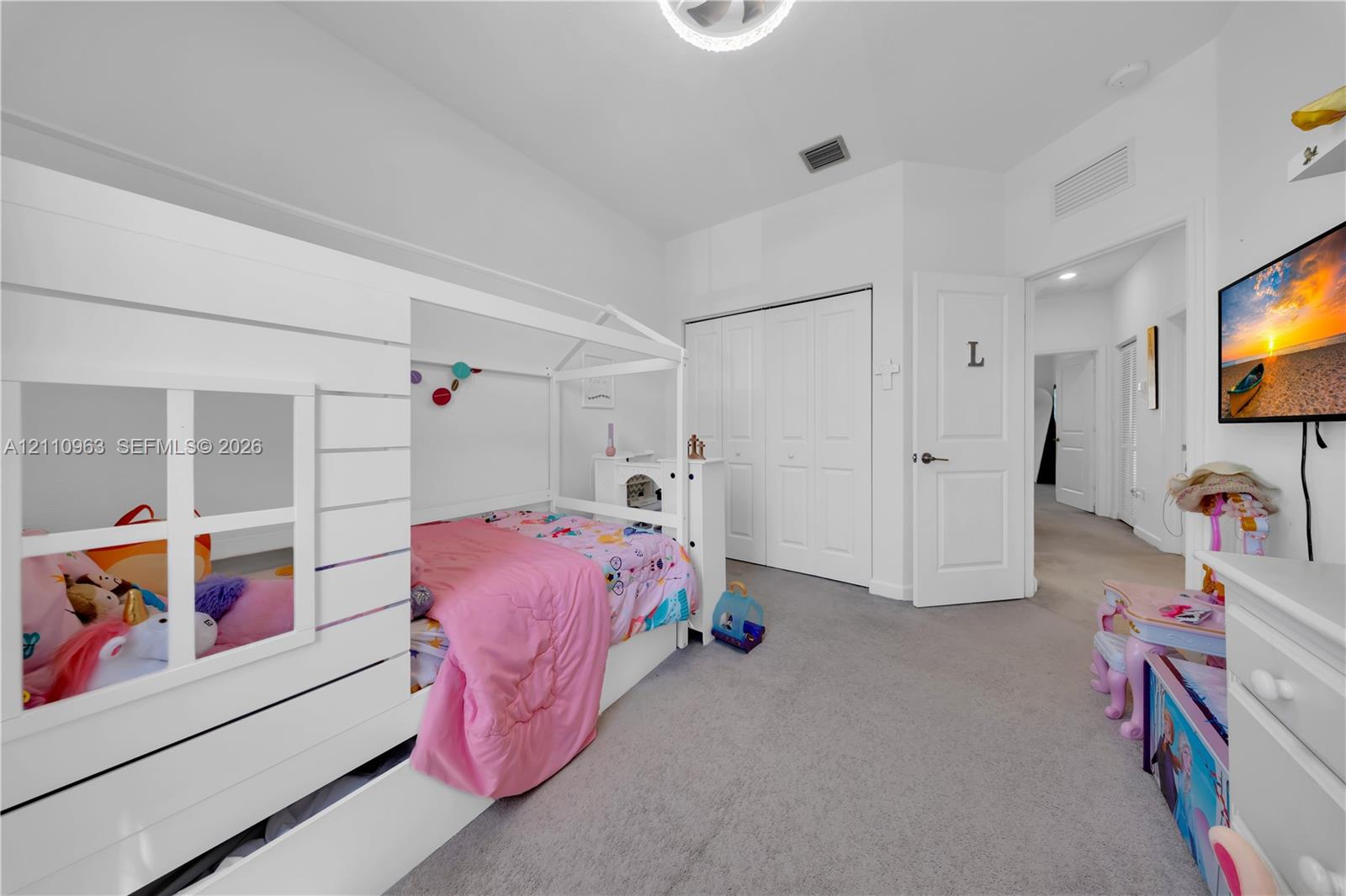 Bedroom featuring neutral wall-to-wall carpeting, multi-panel closet doors, and an overhead flush-mount light fixture
