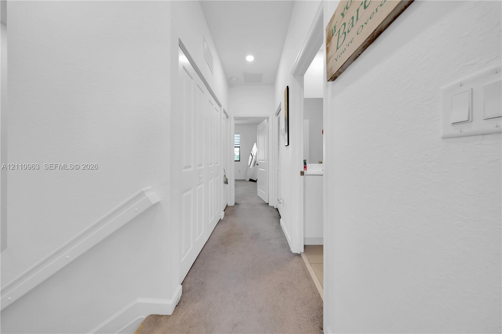 Hallway featuring neutral carpeting, multi-panel doors, and recessed lighting